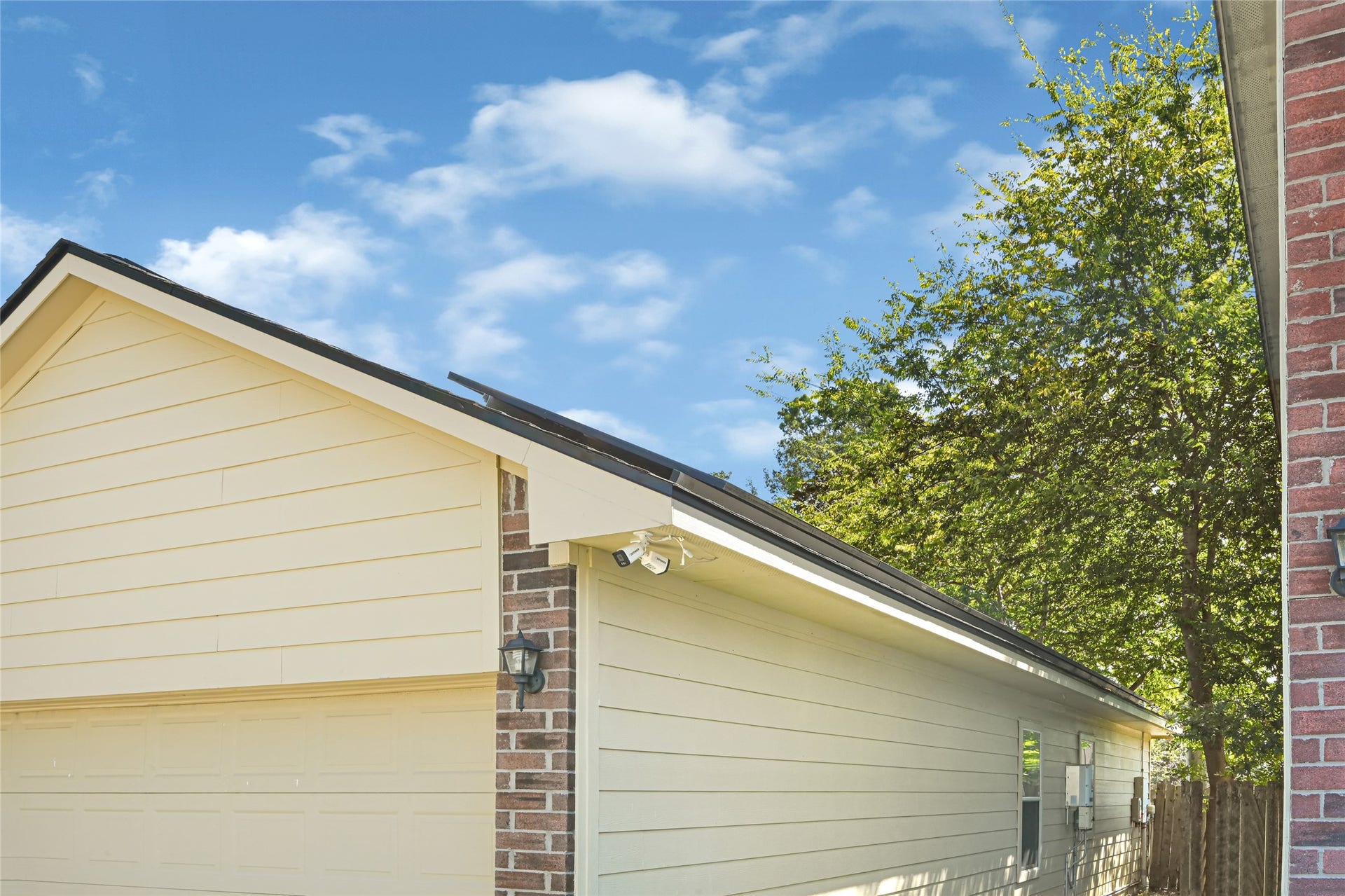 Close up view of the brick & siding exterior of the house along with security cameras (Not included with the sale of the house).