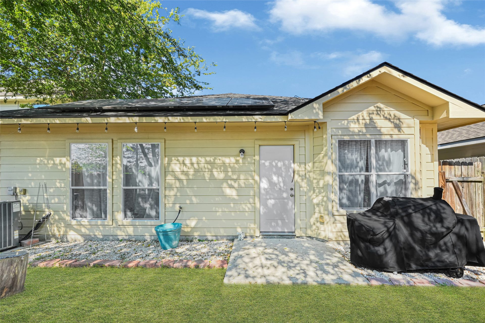 Charming backyard featuring a cozy patio area with string lights, perfect for relaxation and outdoor gatherings.