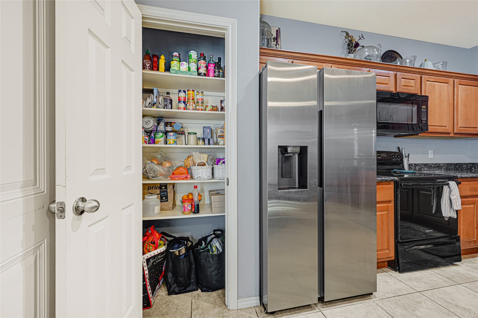 A six later pantry for plenty of storage of dry goods alongside a large steel refrigerator that is to be included in the sale.