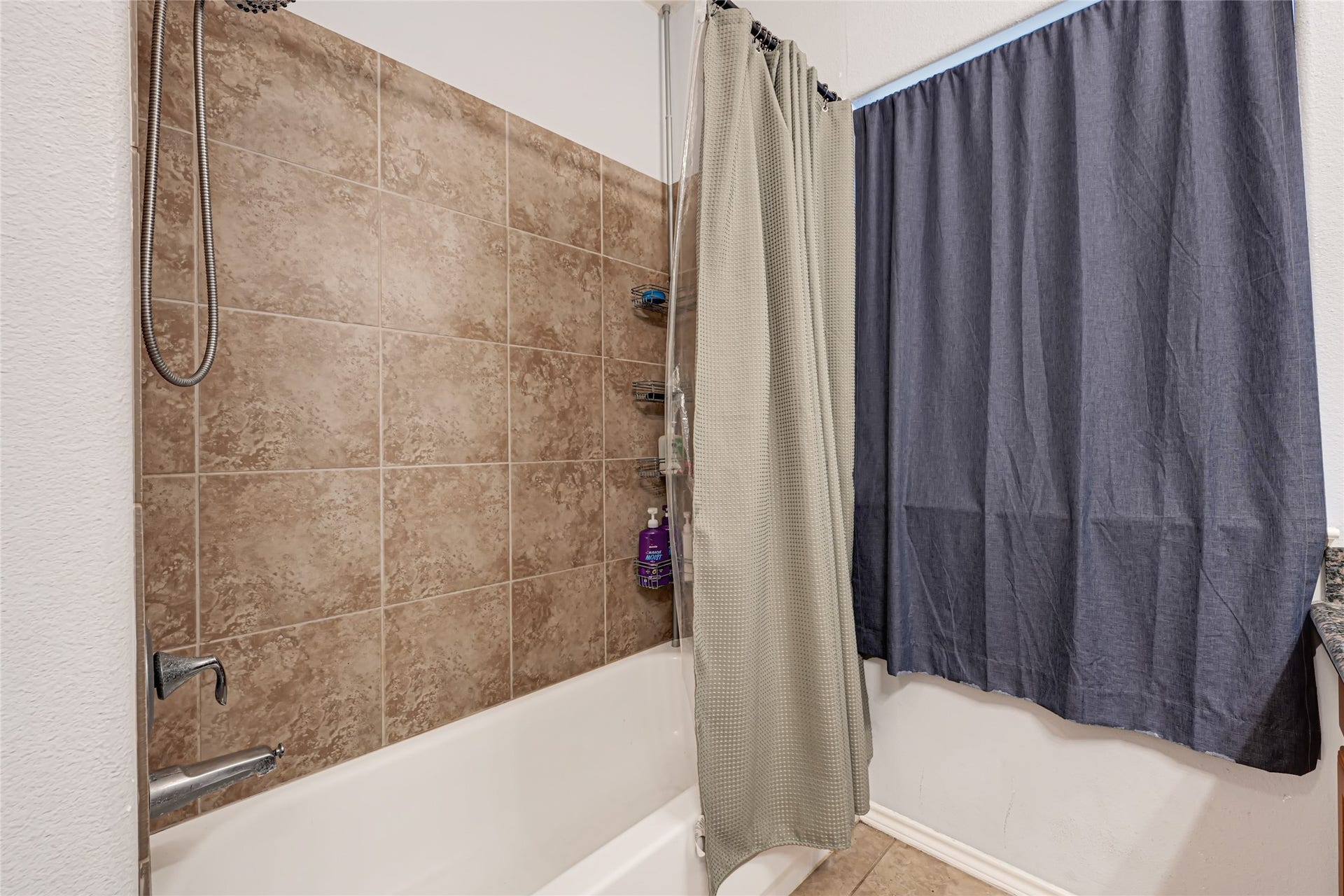 Modern bathroom featuring a stylish tiled shower and bathtub, complemented by a sleek curtain for added privacy.
