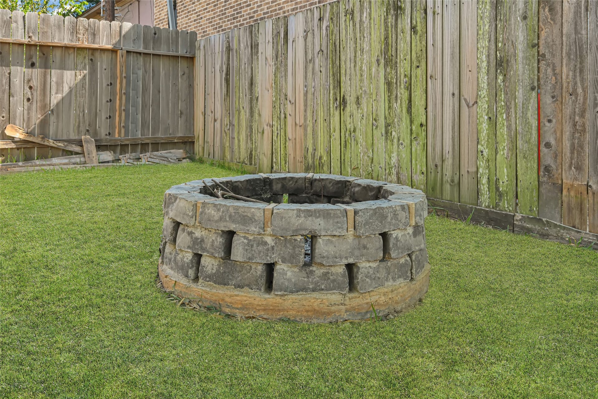 Charming backyard with a rustic stone fire pit, perfect for cozy outdoor gatherings.