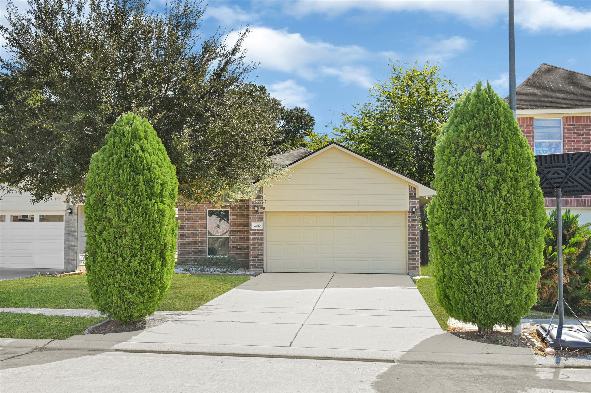 Charming brick home with a welcoming faade, featuring a neatly manicured lawn and framed by two tall, elegant trees.