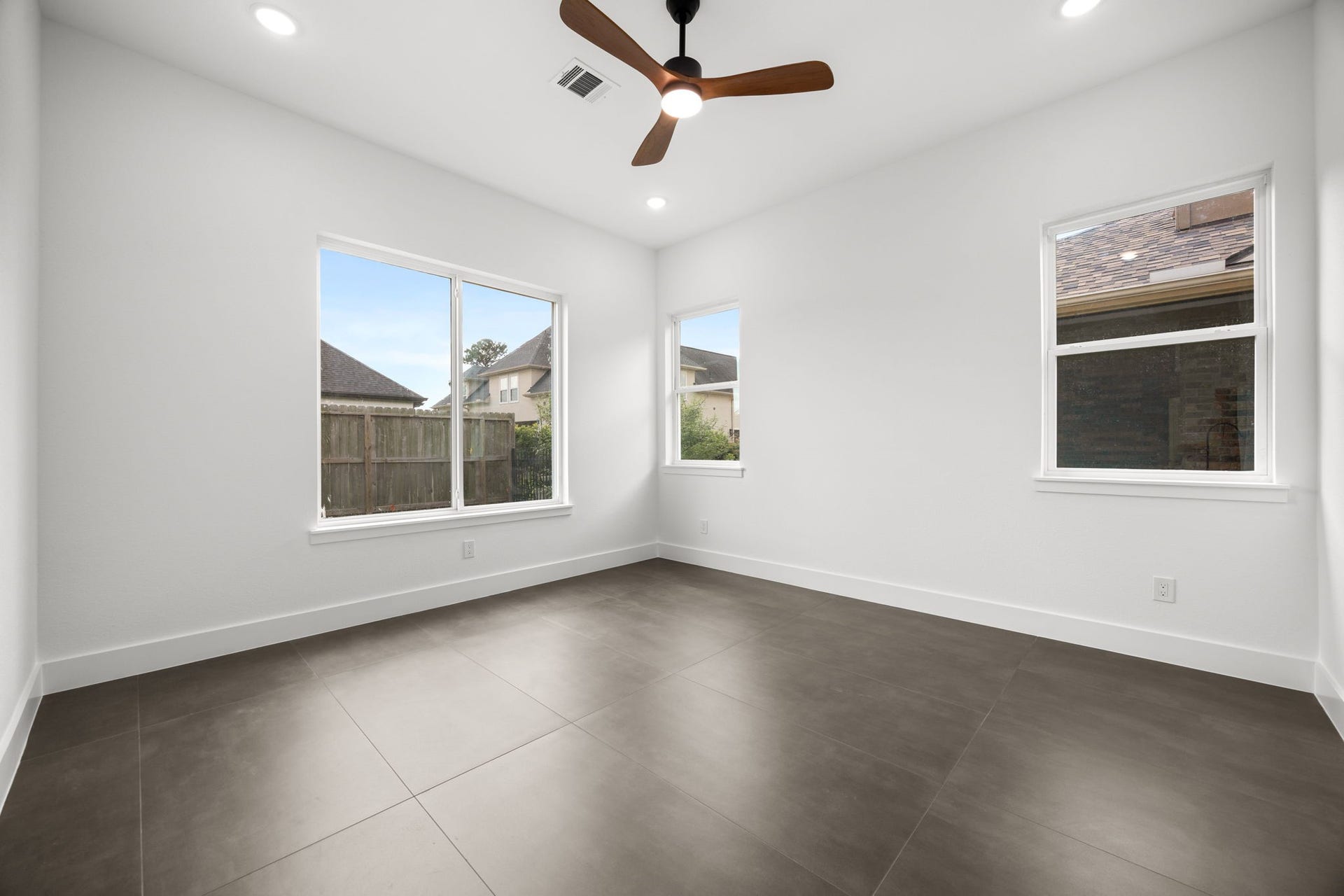 98 Camden Hills Drive, Montgomery, TX 77356 This bright room features large windows, neutral-colored tile flooring, and a ceiling fan, providing a modern and airy feel.