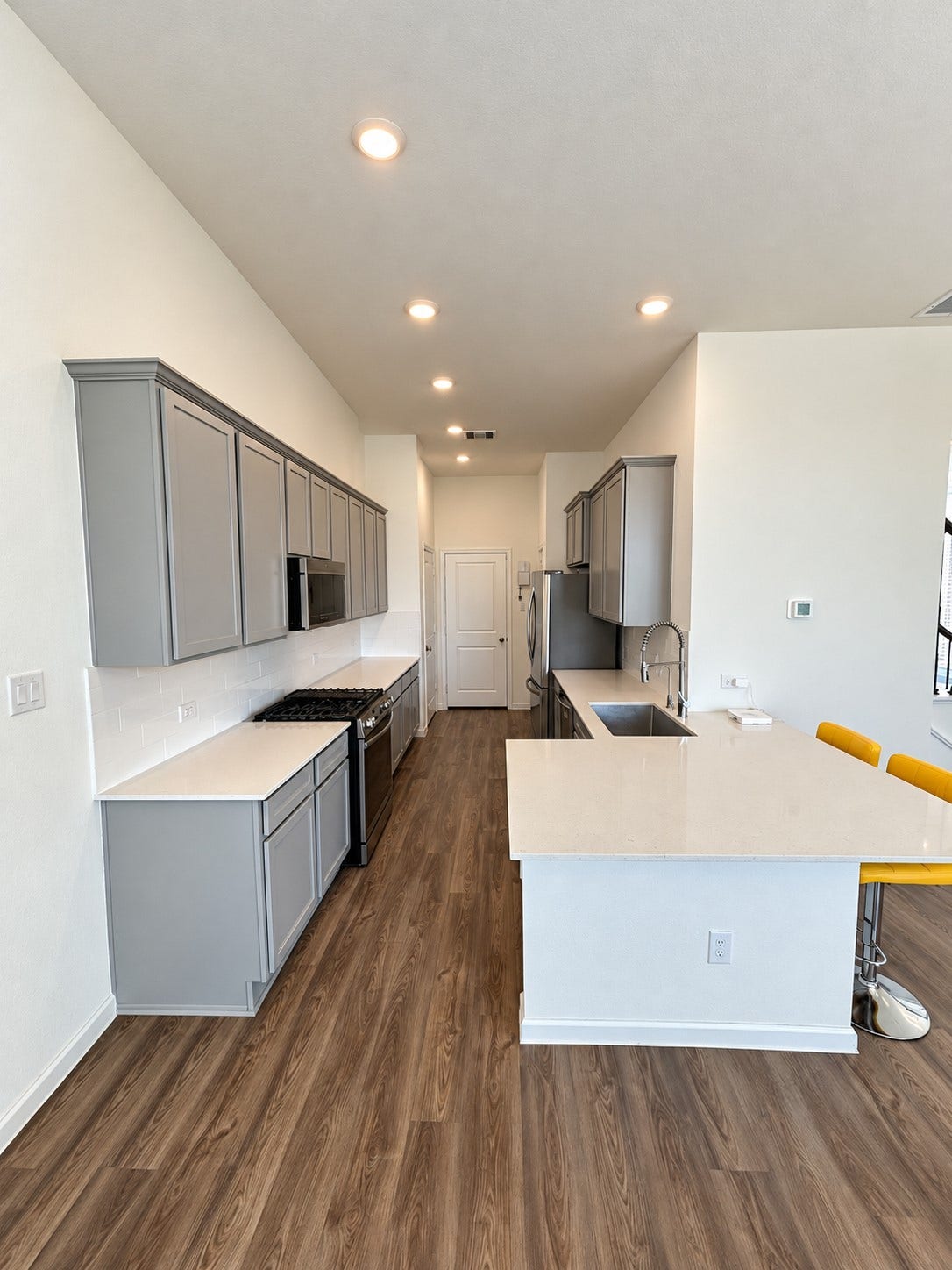 4. Kitchen with gray cabinetry, stainless steel appliances, and an island with seating.