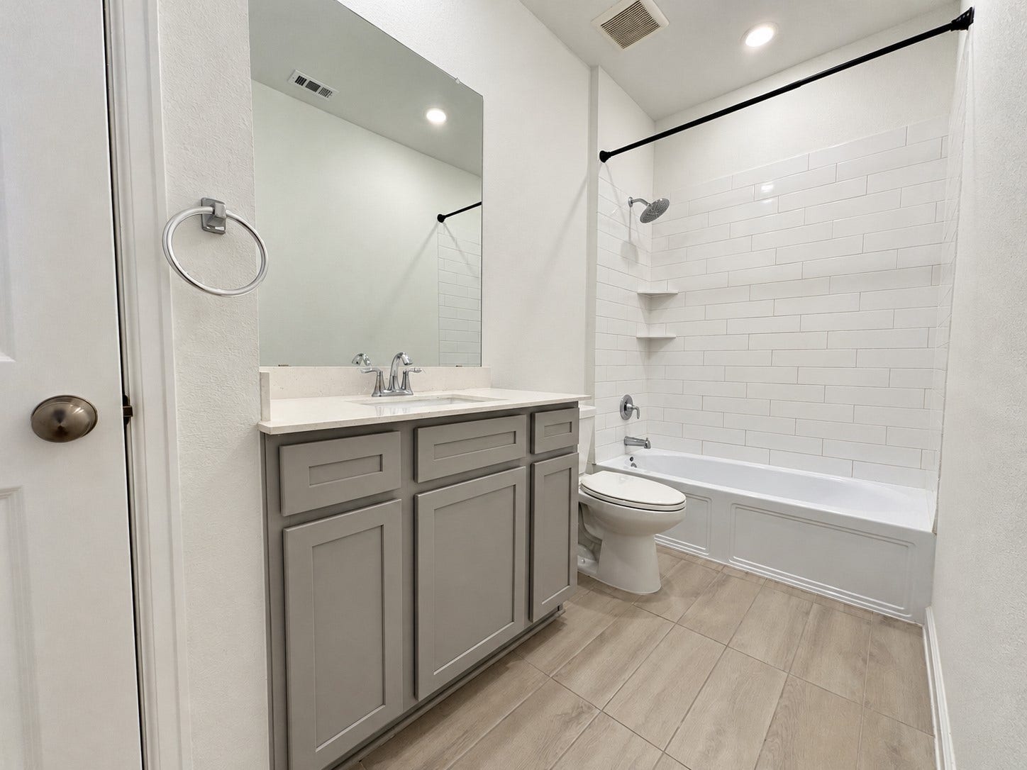 13. Hall bathroom with a gray vanity and a tiled tub-and-shower combination.