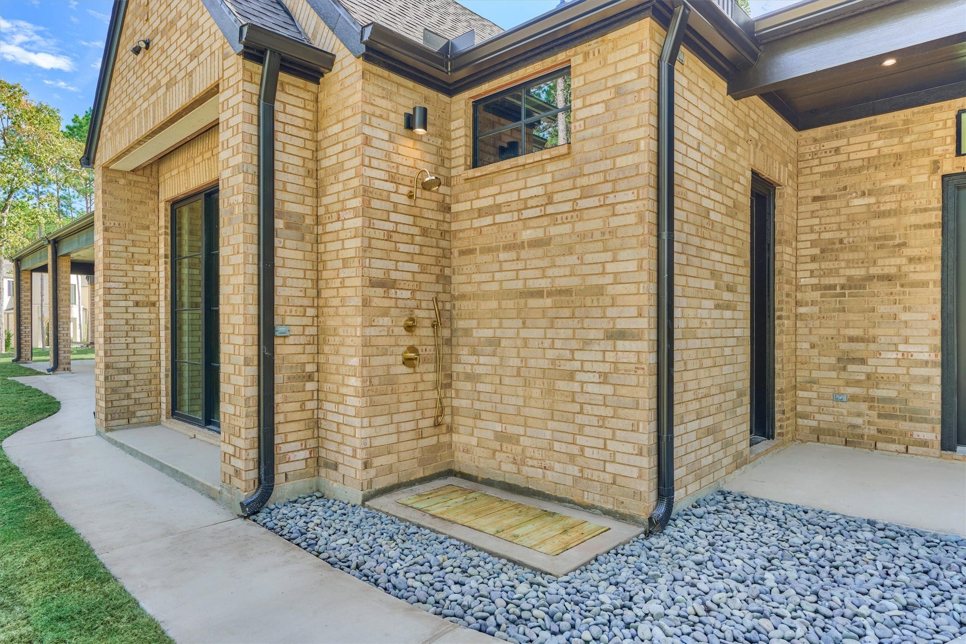 4800 Hawk Canyon Court, Montgomery, TX 77316 Outdoor shower retreat featuring black stone accents, wooden platform and gold finishes, blending organic beauty with modern luxury.
