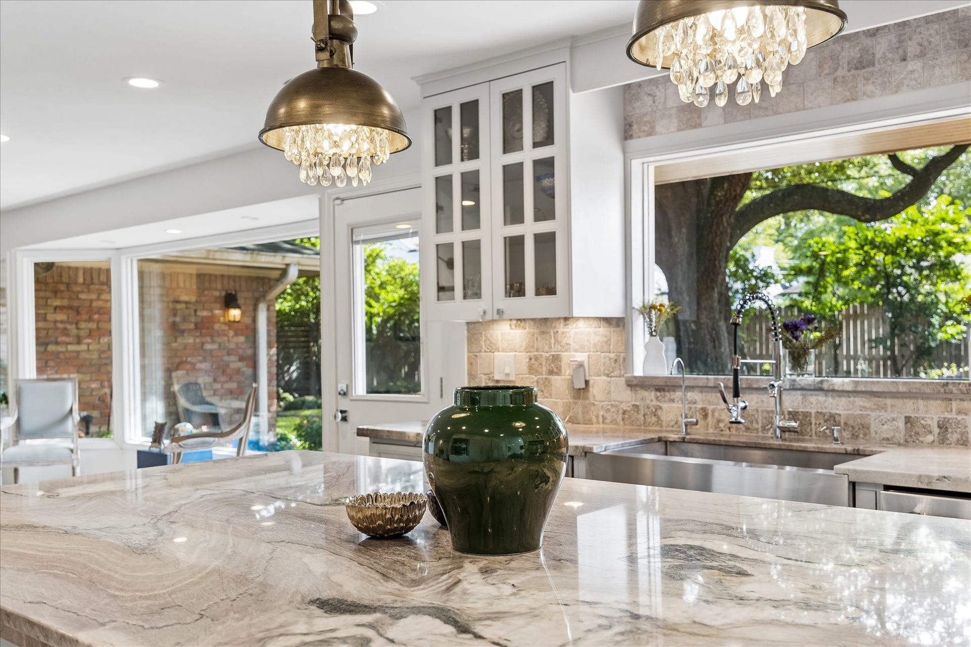4703 Banning Drive, Houston, TX 77027 Closer look at the gorgeous stone countertops, decorative pendant lighting & farmhouse-style stainless steel sink w/statement faucet. Large windows bring in natural light & offer views of the backyard.