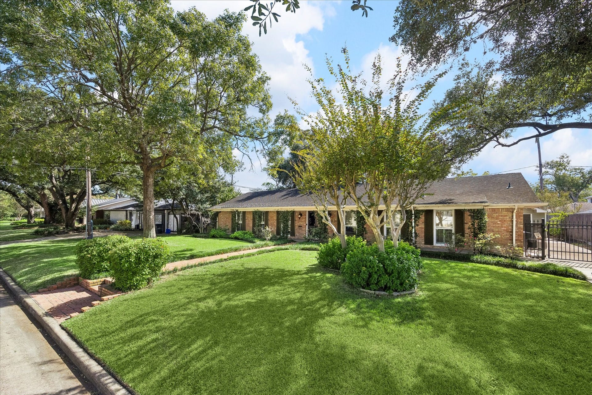 4703 Banning Drive, Houston, TX 77027 Beautiful one-story brick home in Afton Oaks, surrounded by mature trees & lush landscaping. Expansive front lawn, manicured hedges, & gated driveway add to the inviting exterior.