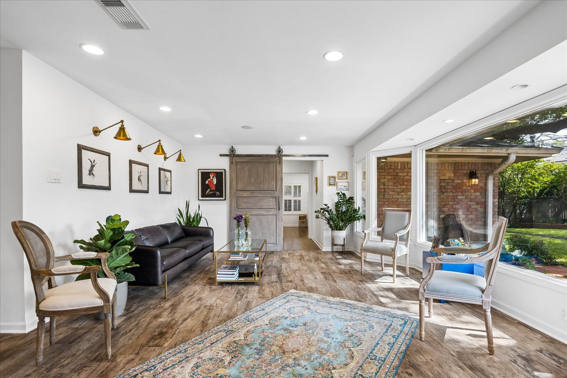 4703 Banning Drive, Houston, TX 77027 Bright & inviting living area features wood flooring, recessed lighting, decorative wall sconces & a sliding barn door. Large windows bring in natural light & offer beautiful views of the backyard.