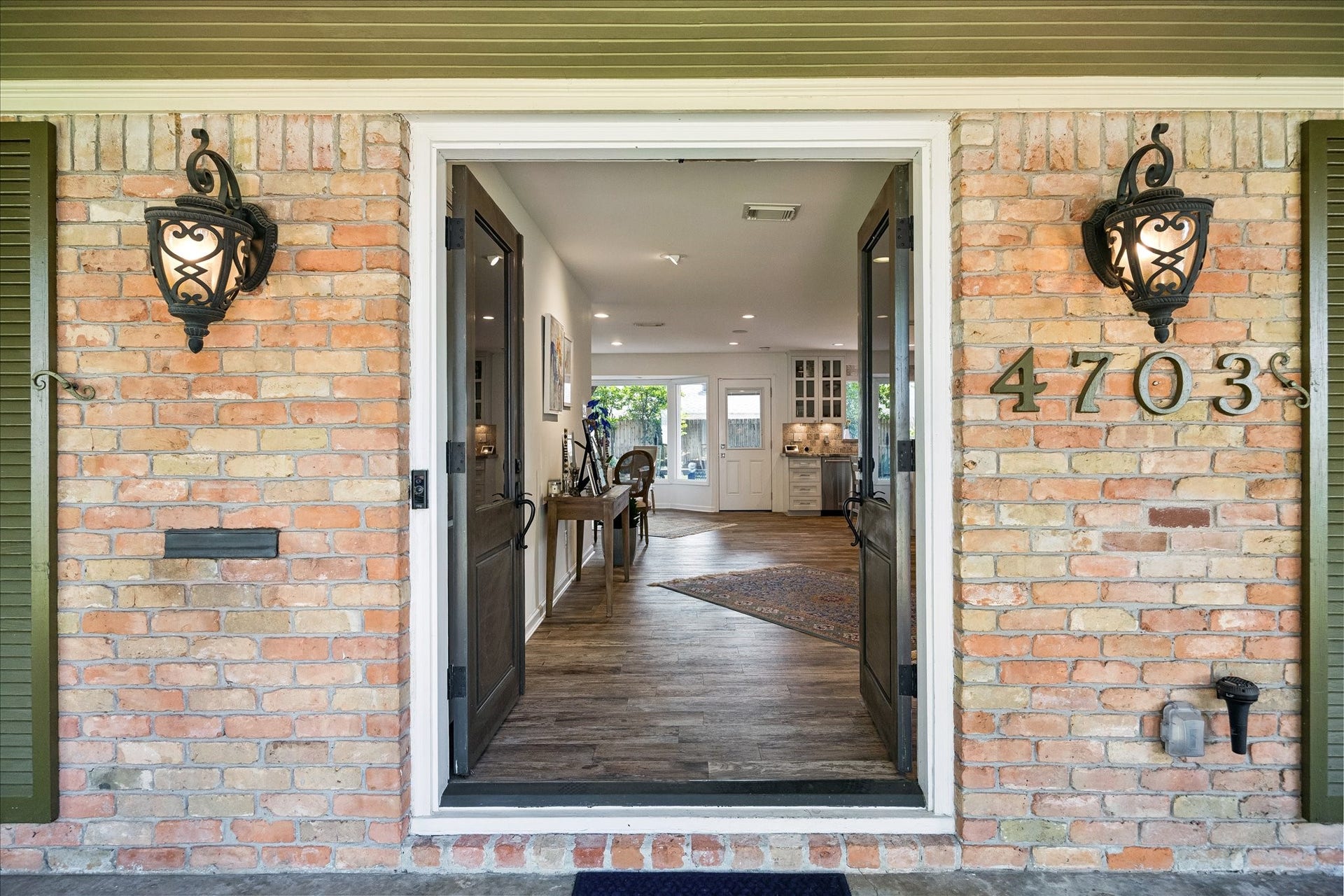 4703 Banning Drive, Houston, TX 77027 Welcoming double-door entry framed by brick accents & decorative lanterns opens to an inviting interior w/wood flooring & views into the living spaces beyond.