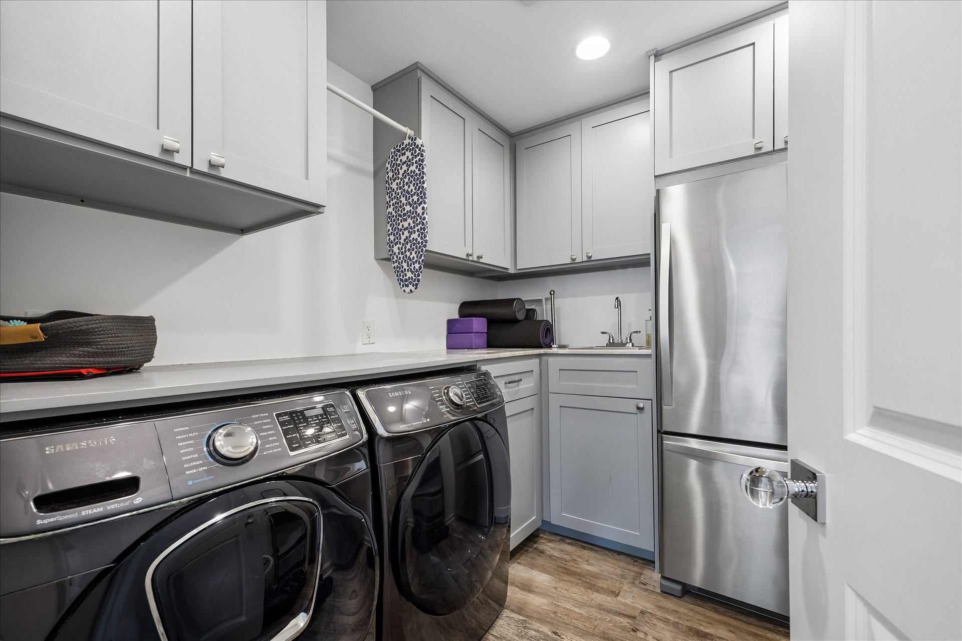 4703 Banning Drive, Houston, TX 77027 Well-appointed utility room features full-size washer & dryer, extensive upper & lower cabinetry, countertop workspace, utility sink & additional refrigerator. Recessed lighting & wood-look flooring complete this functional space, offering excellent storage & convenience for everyday household needs.