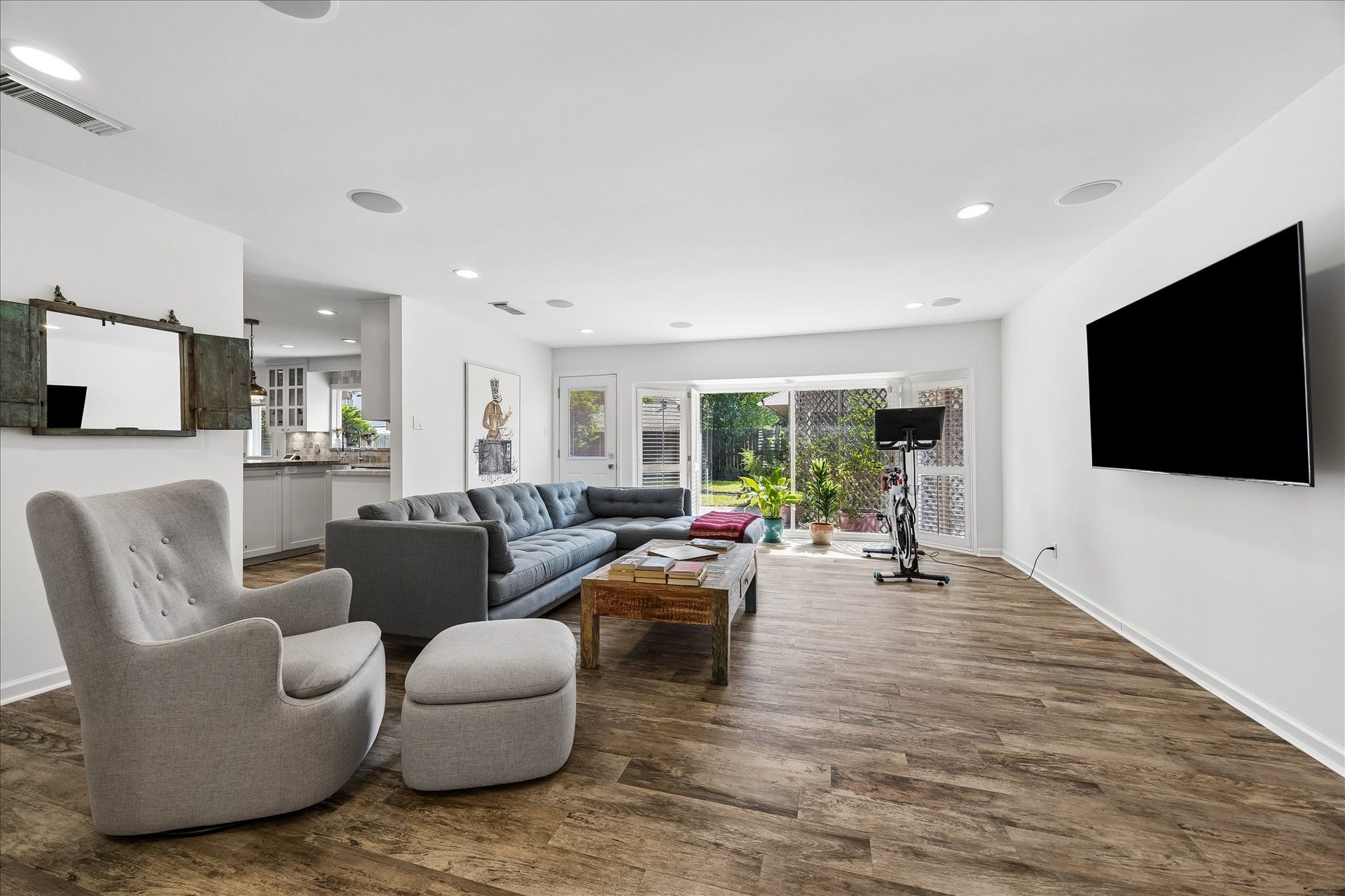 4703 Banning Drive, Houston, TX 77027 Spacious den offers a wonderful secondary living area w/wood-look flooring, recessed lighting, built-in ceiling speakers & a wall-mounted TV. Large windows overlook the backyard, filling the space w/natural light.