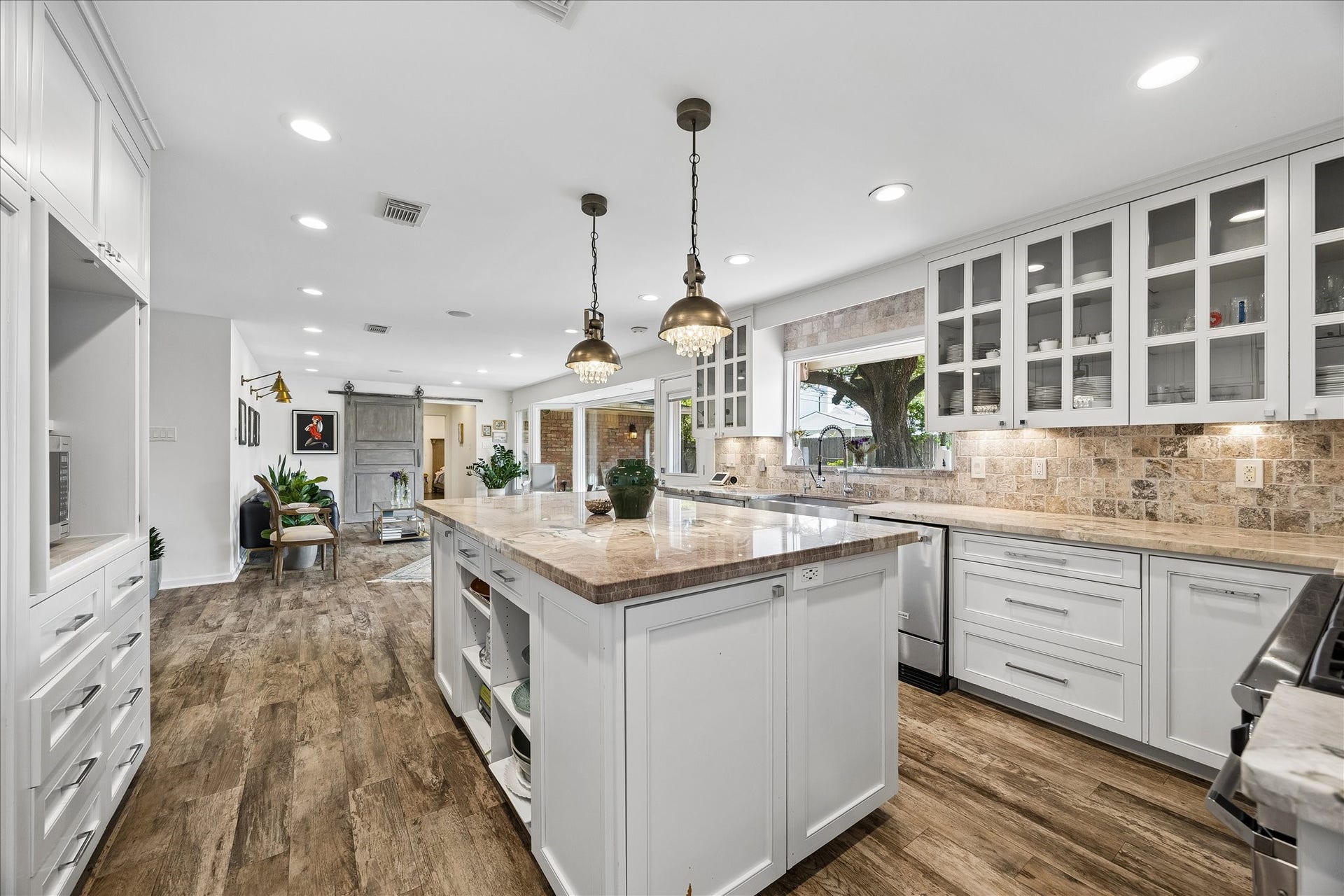 4703 Banning Drive, Houston, TX 77027 Expansive kitchen showcases an oversized island w/stone countertop, extensive cabinetry, under-cabinet lighting & wood flooring. Open layout flows seamlessly into the adjoining living area, ideal for entertaining.