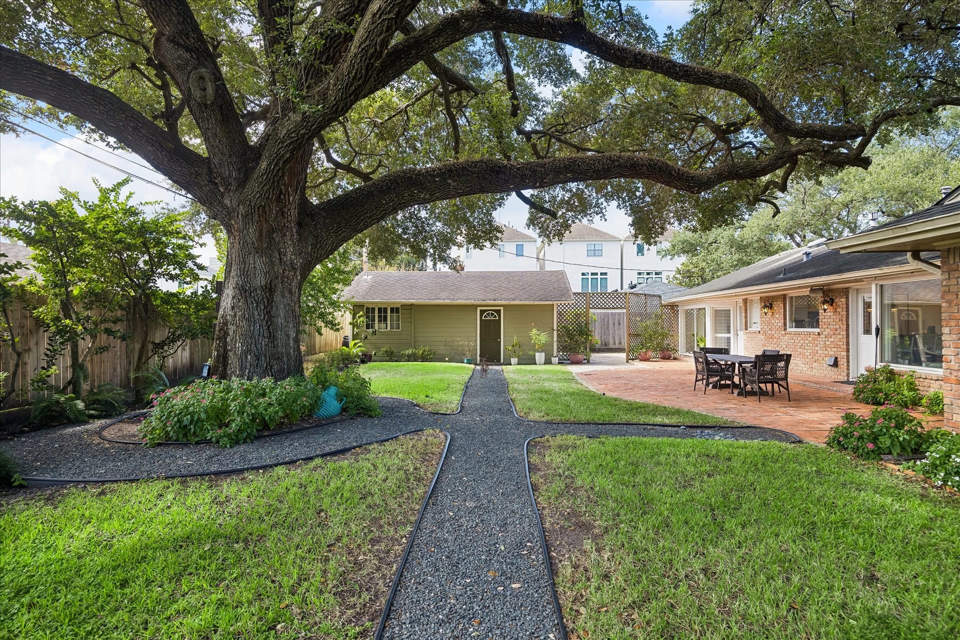 4703 Banning Drive, Houston, TX 77027 Beautiful backyard features a magnificent mature oak tree as its centerpiece, surrounded by landscaped garden beds & winding pathways. The expansive brick patio connects to the home, offering an ideal setting for outdoor gatherings.