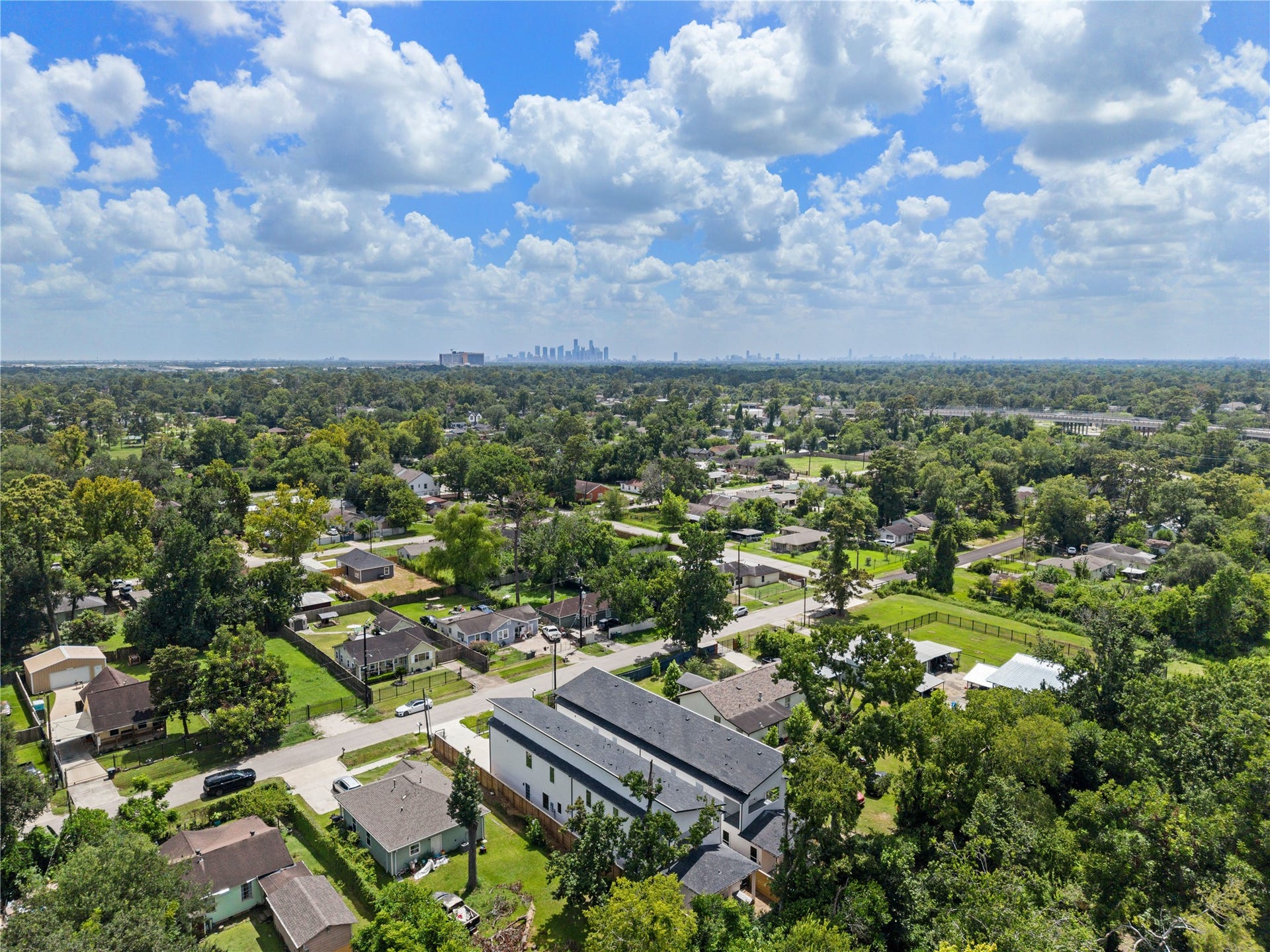 Scenic aerial view of the neighborhood with with Downtown Houston in the distant city skyline, offering a convenient location to Downtown Houston and LBJ Hospital.