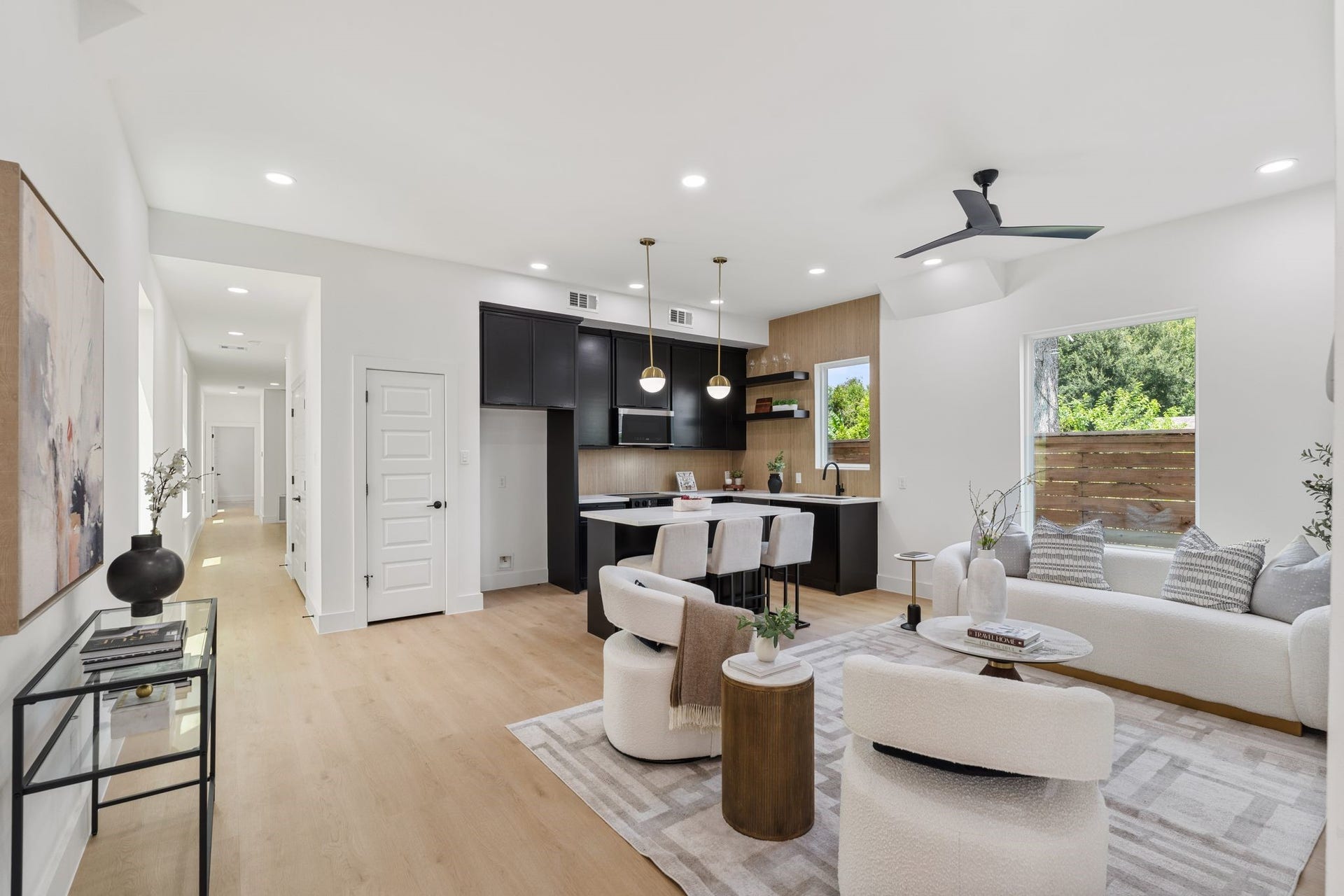 Bright and spacious open-concept living area featuring a modern kitchen with sleek cabinetry,cozy seating, and large windows that invite natural light, perfect for entertaining or relaxing.