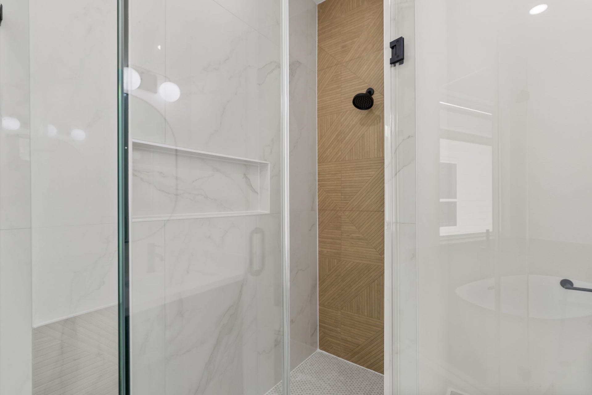 Sleek and modern shower featuring elegant marble look tiles and a stylish wood-patterned accent wall, complemented by a matte black showerhead. Spacious covered