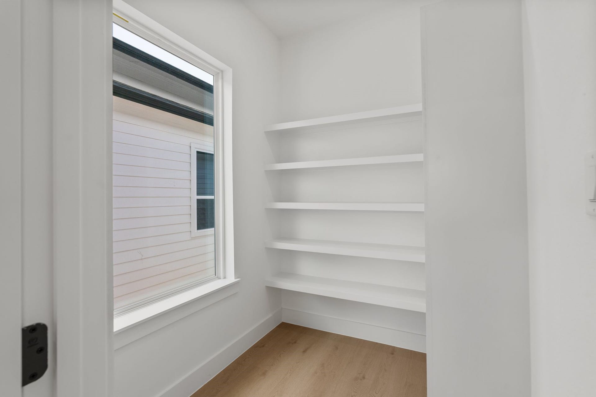 Bright and airy storage space featuring built-in shelves and a large window for natural light.