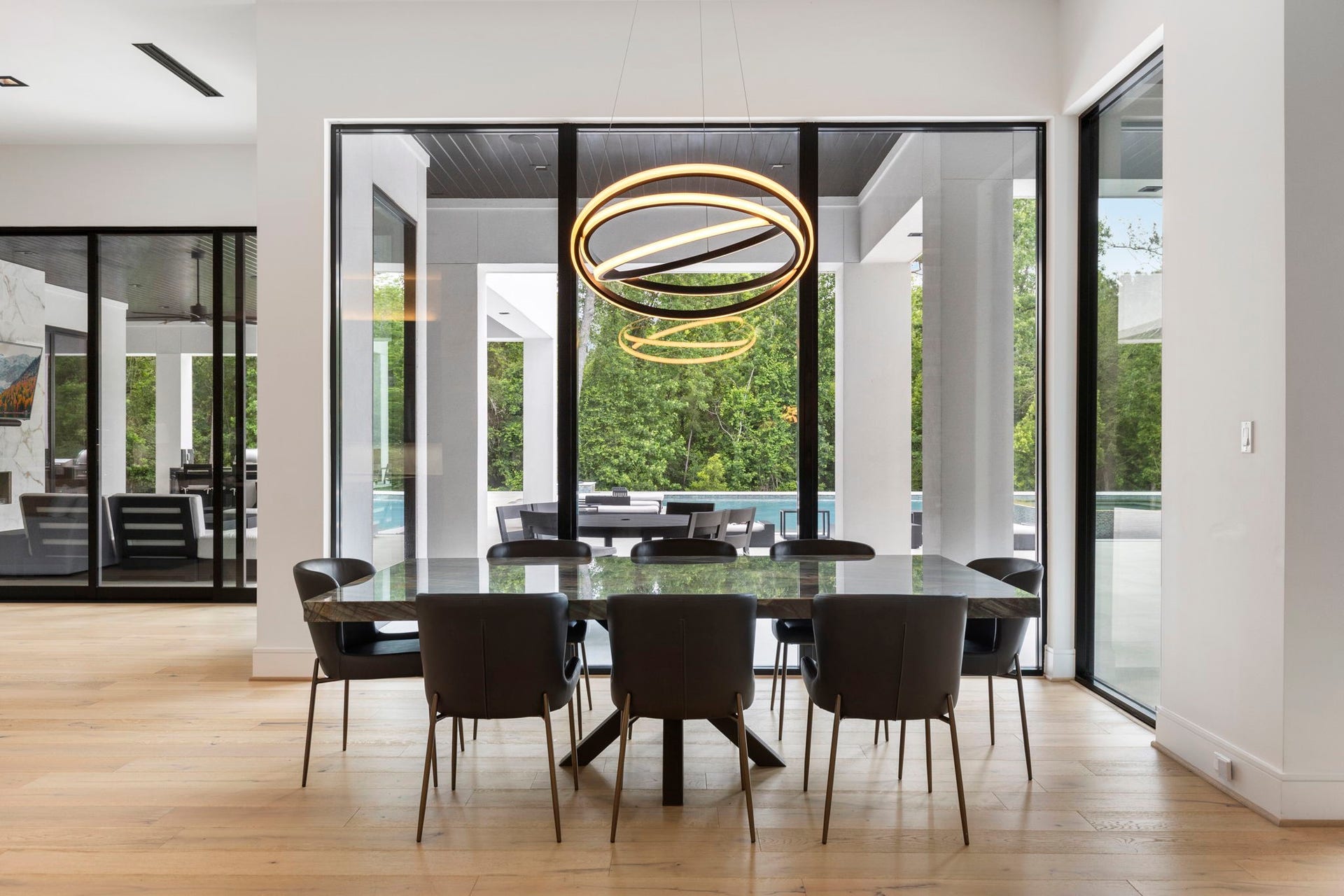 Positioned adjacent to the chef's kitchen and family room, the sunlit breakfast space offers an exquisite, custom natural-edge table and striking light fixture.