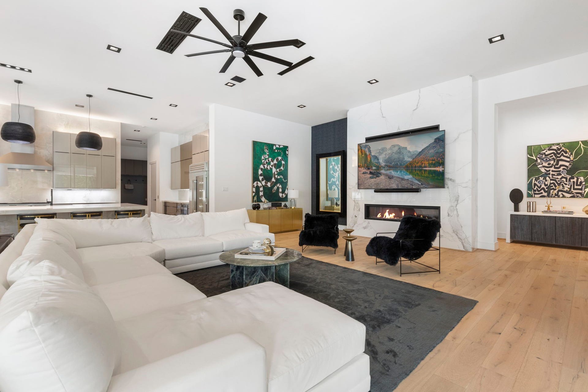 The family room blends contemporary elegance with inviting comfort, anchored by a dramatic marble statement wall and sleek linear fireplace.