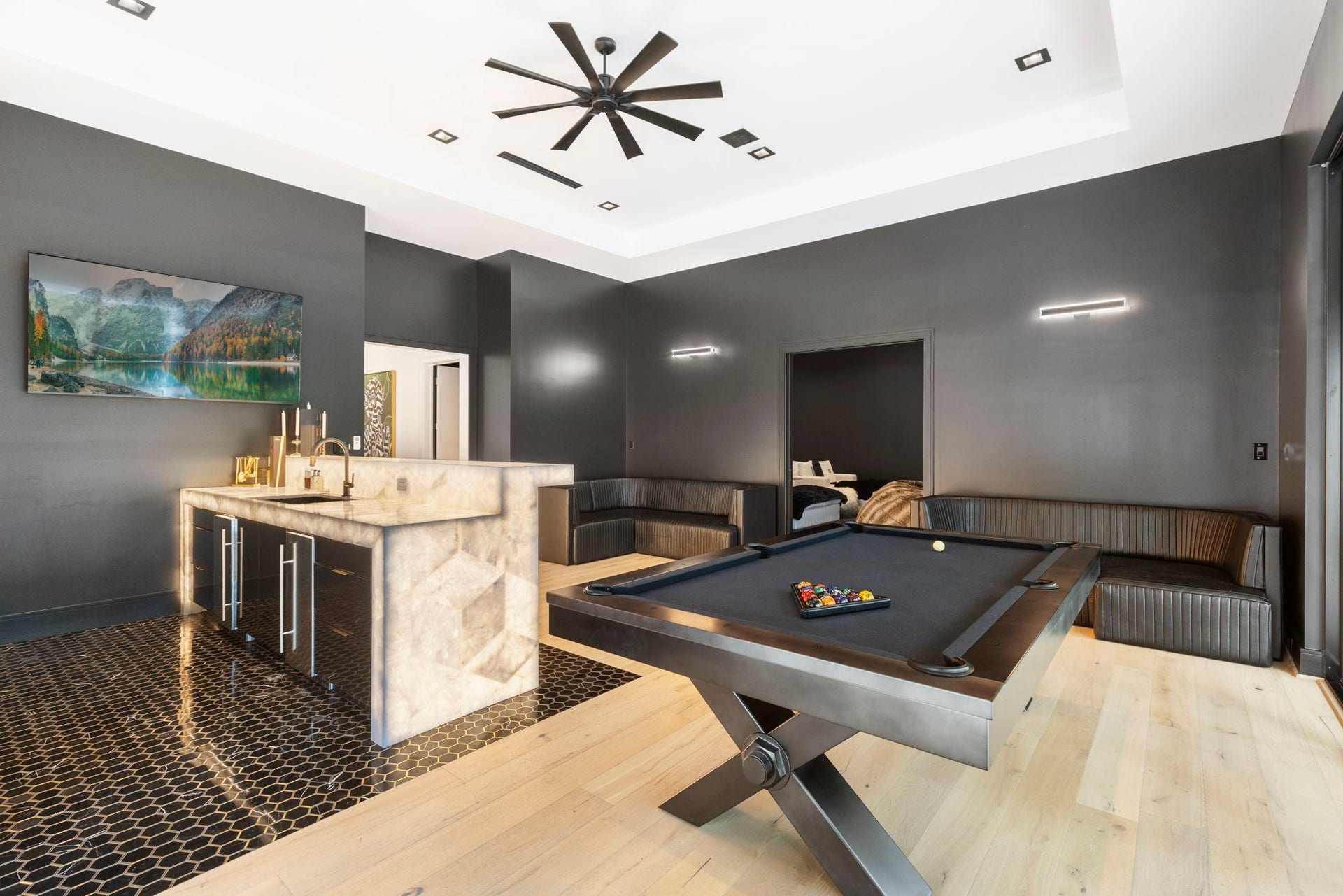 Located on the first floor featuring a stunning backlit quartz wet bar, billiards area, and built-in seating, this game room opens to the patio for extended entertaining space.