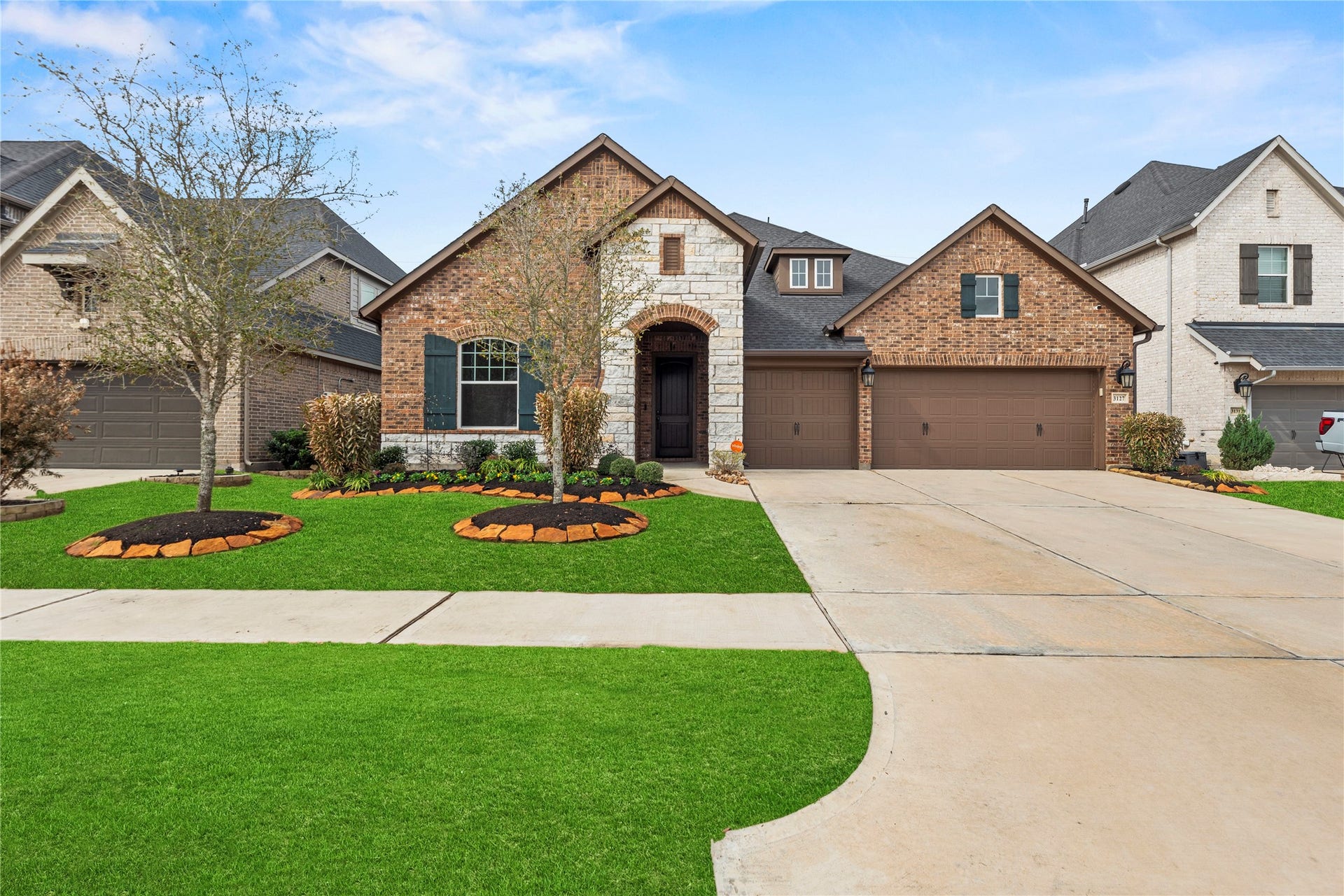 3127 Swift Way, Katy, TX 77493 Charming brick and stone facade with manicured landscaping and a spacious three-car garage, nestled in a picturesque neighborhood.