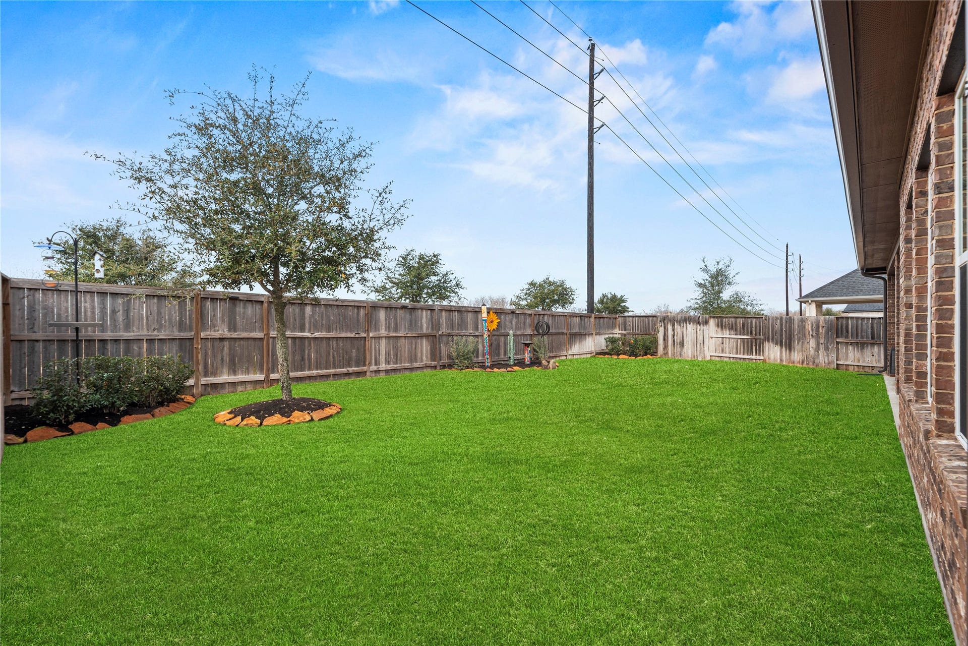 3127 Swift Way, Katy, TX 77493 Spacious backyard with lush green lawn, mature tree, and privacy fence, perfect for outdoor activities and relaxation.
