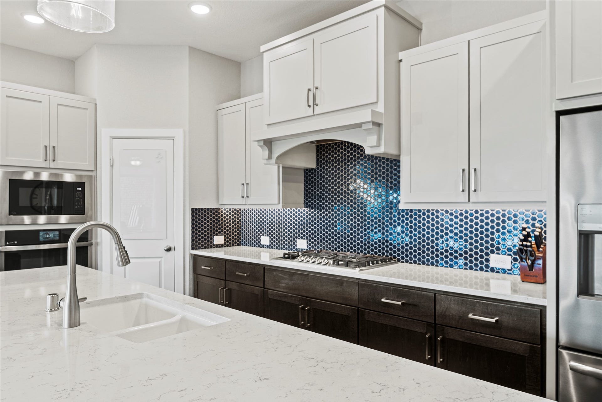 3127 Swift Way, Katy, TX 77493 Sleek kitchen with quartz countertops, stainless steel appliances, and a striking hexagonal tile backsplash, complemented by crisp white cabinetry.