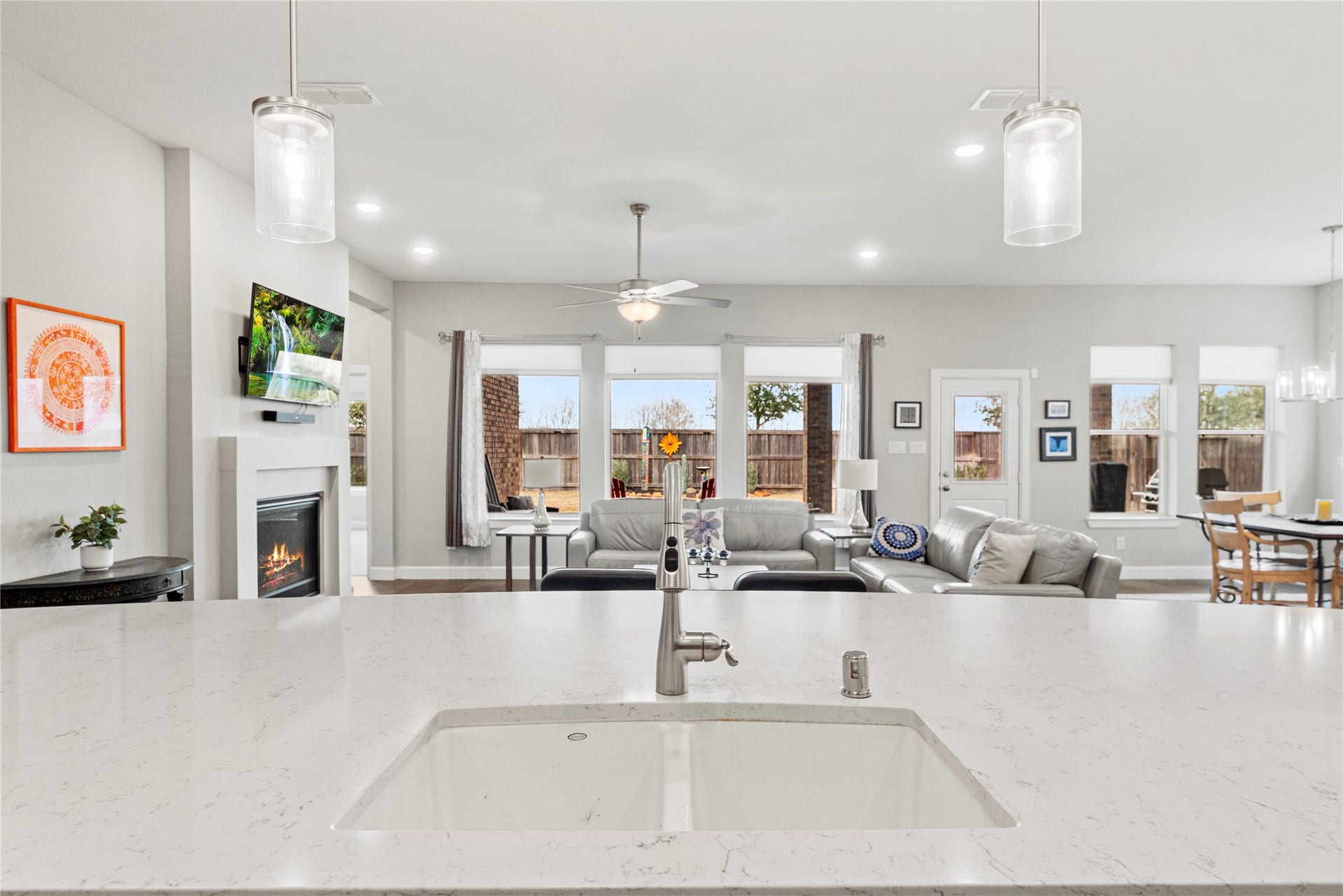 3127 Swift Way, Katy, TX 77493 Spacious open-concept living area with a modern kitchen island, cozy fireplace, and abundant natural light from large windows overlooking the backyard.