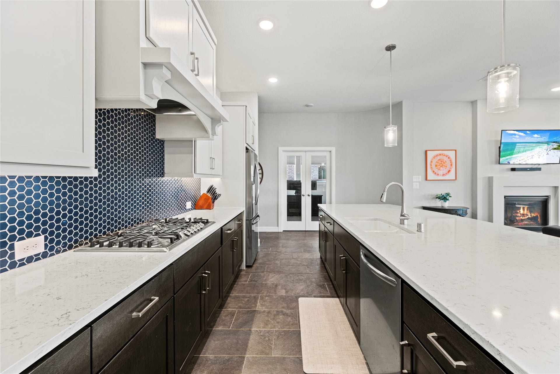 3127 Swift Way, Katy, TX 77493 Sleek modern kitchen featuring a spacious island with elegant pendant lighting, dark cabinetry, and a stunning hexagon tile backsplash.