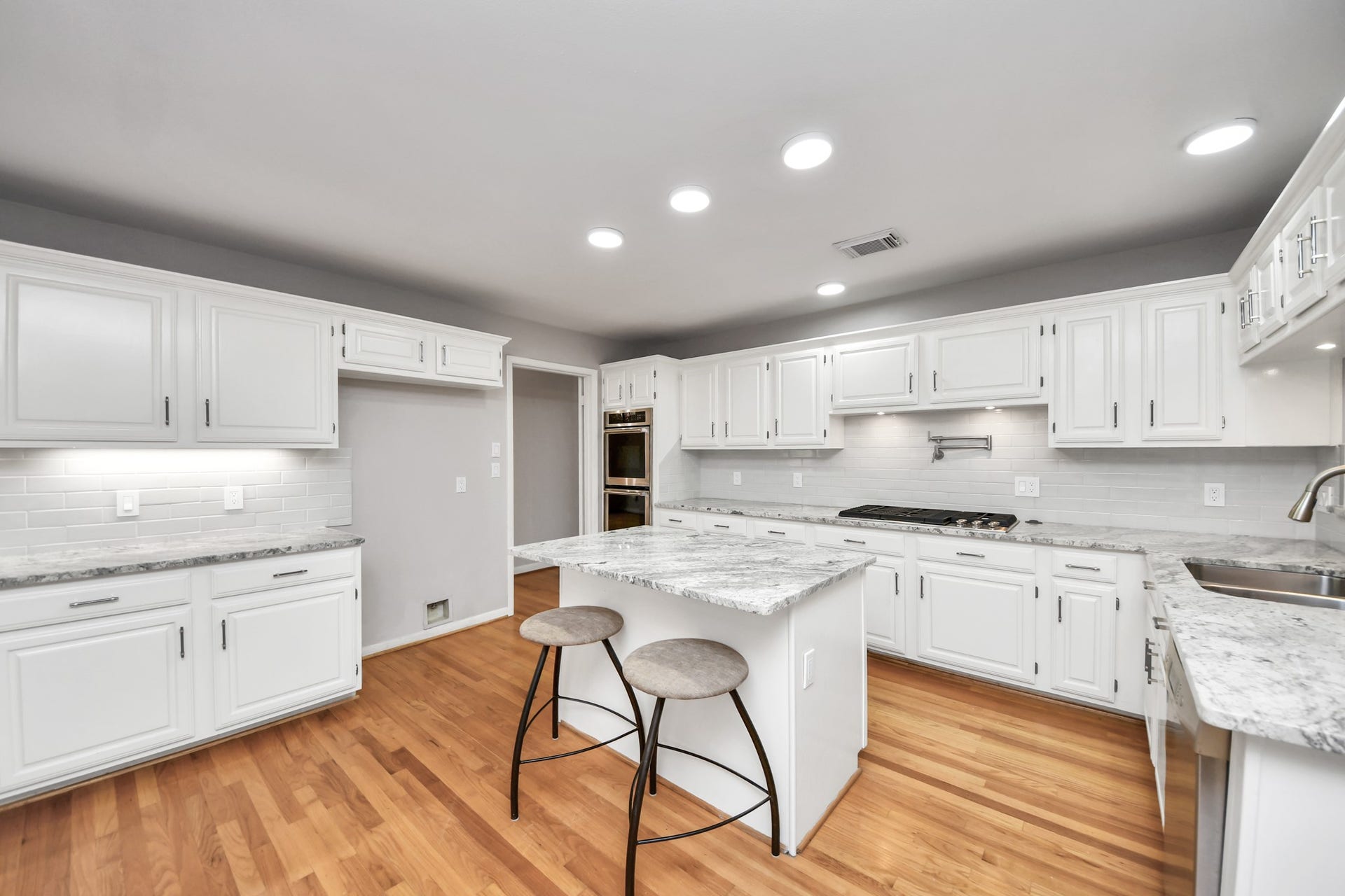 Another view highlights the kitchens generous workspace, KitchenAid gas cooktop with downdraft vent and extensive counter and cabinet space.