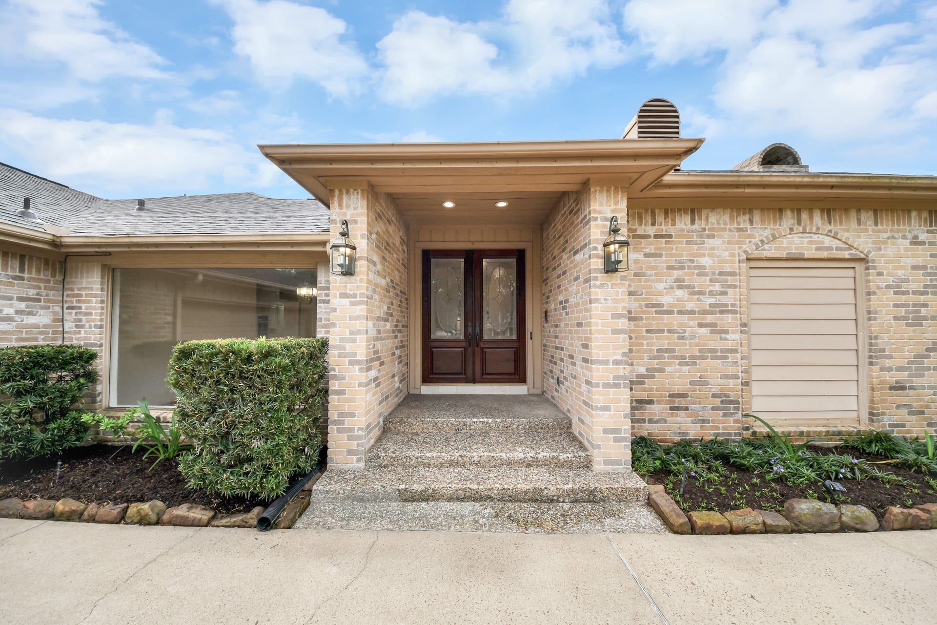 Covered front entry with double doors creates a welcoming arrival and provides a closer look at the homes classic brick exterior.
