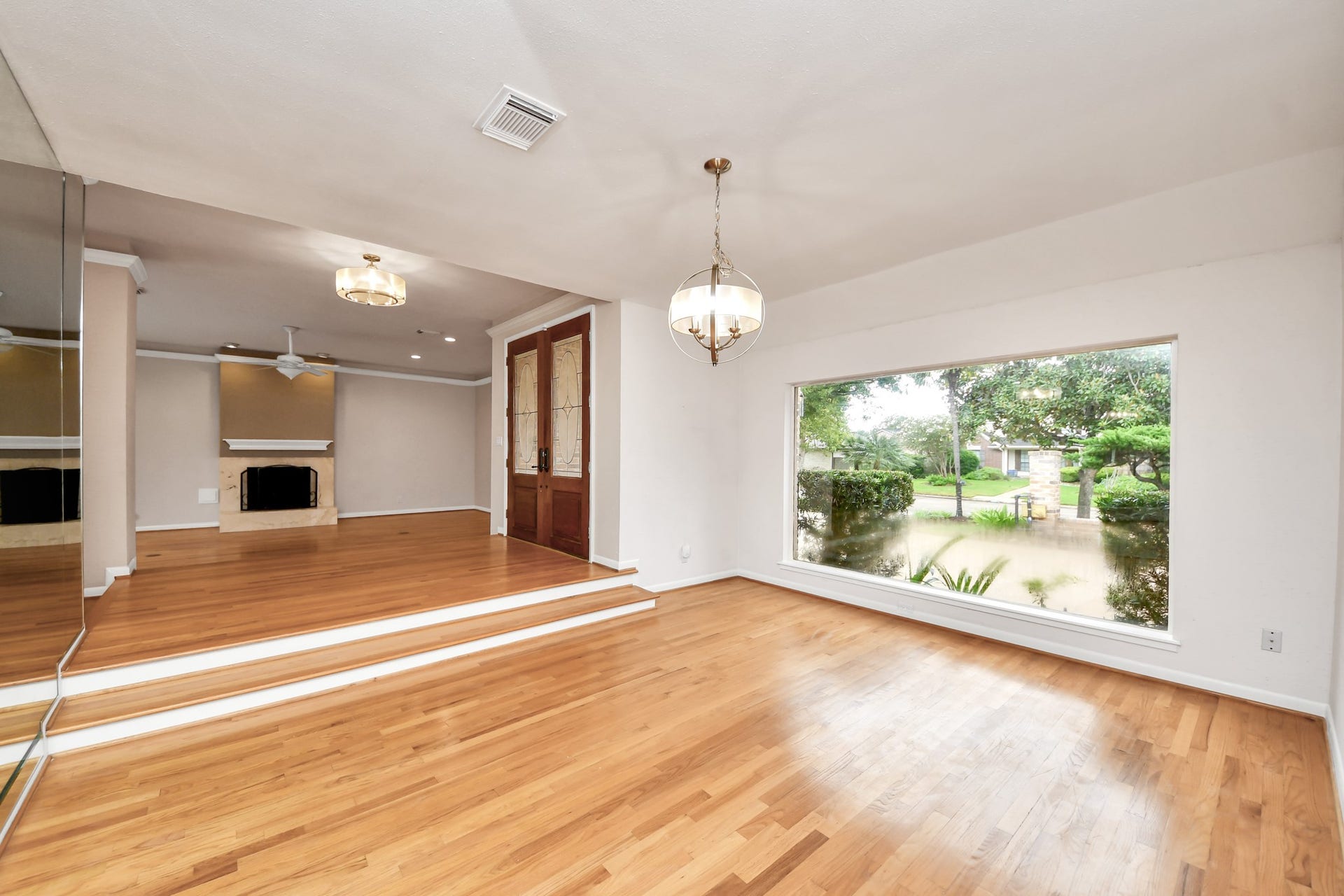 The oversized seamless picture window is a standout feature, bringing natural light and front garden views into the dining room. Wood floors and designer lighting complete the space.
