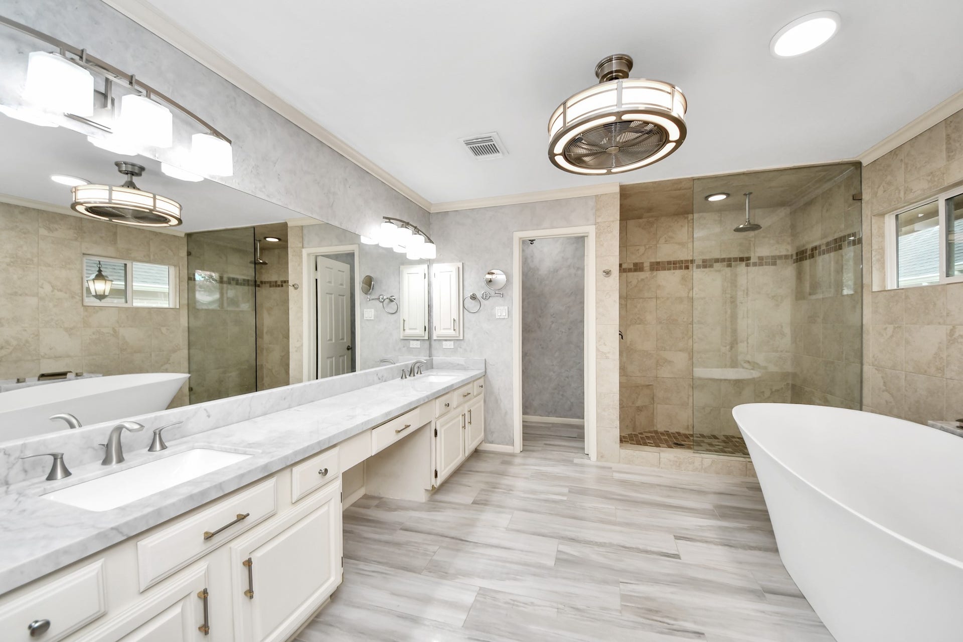 The spacious primary bath continues with a long dual-sink vanity, abundant cabinetry and a large glass-enclosed shower.