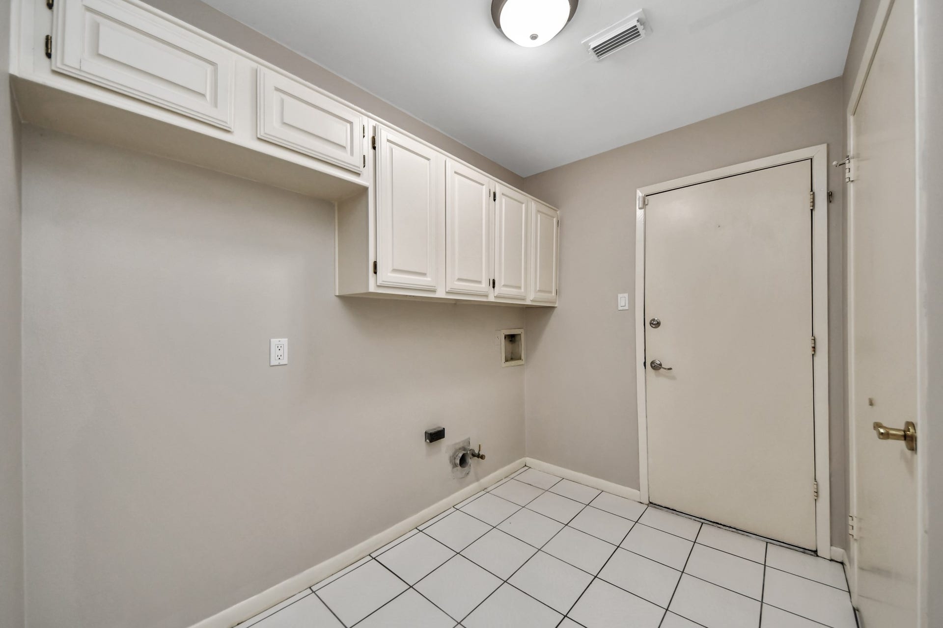 Dedicated utility room offers extensive built-in cabinetry and space for a full-size washer and dryer.