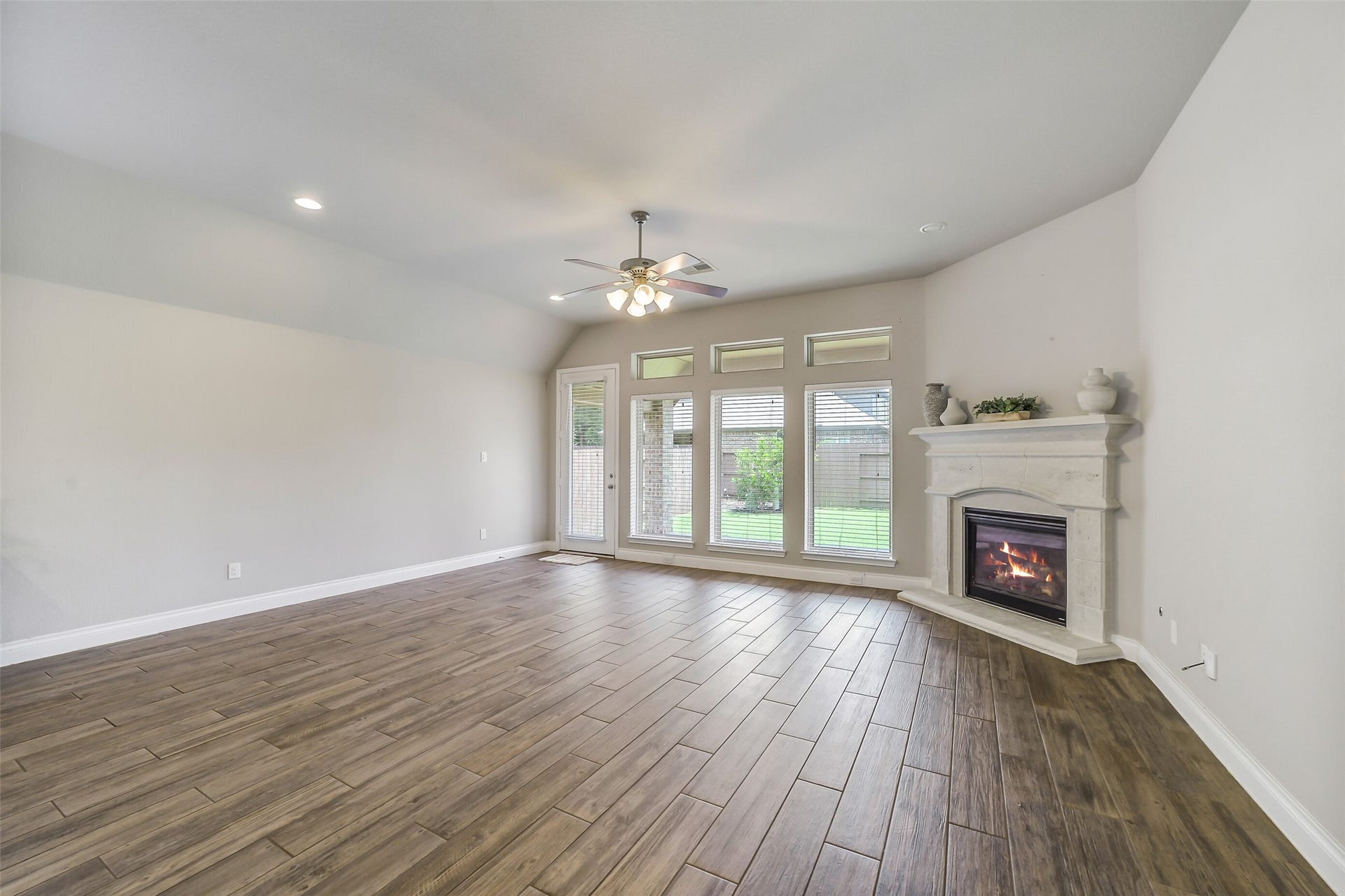 16818 Headwaters Forest Drive, Humble, TX 77346 Bright and spacious living room featuring a cozy corner fireplace, expansive windows, and backyard views that fill the space with natural light.