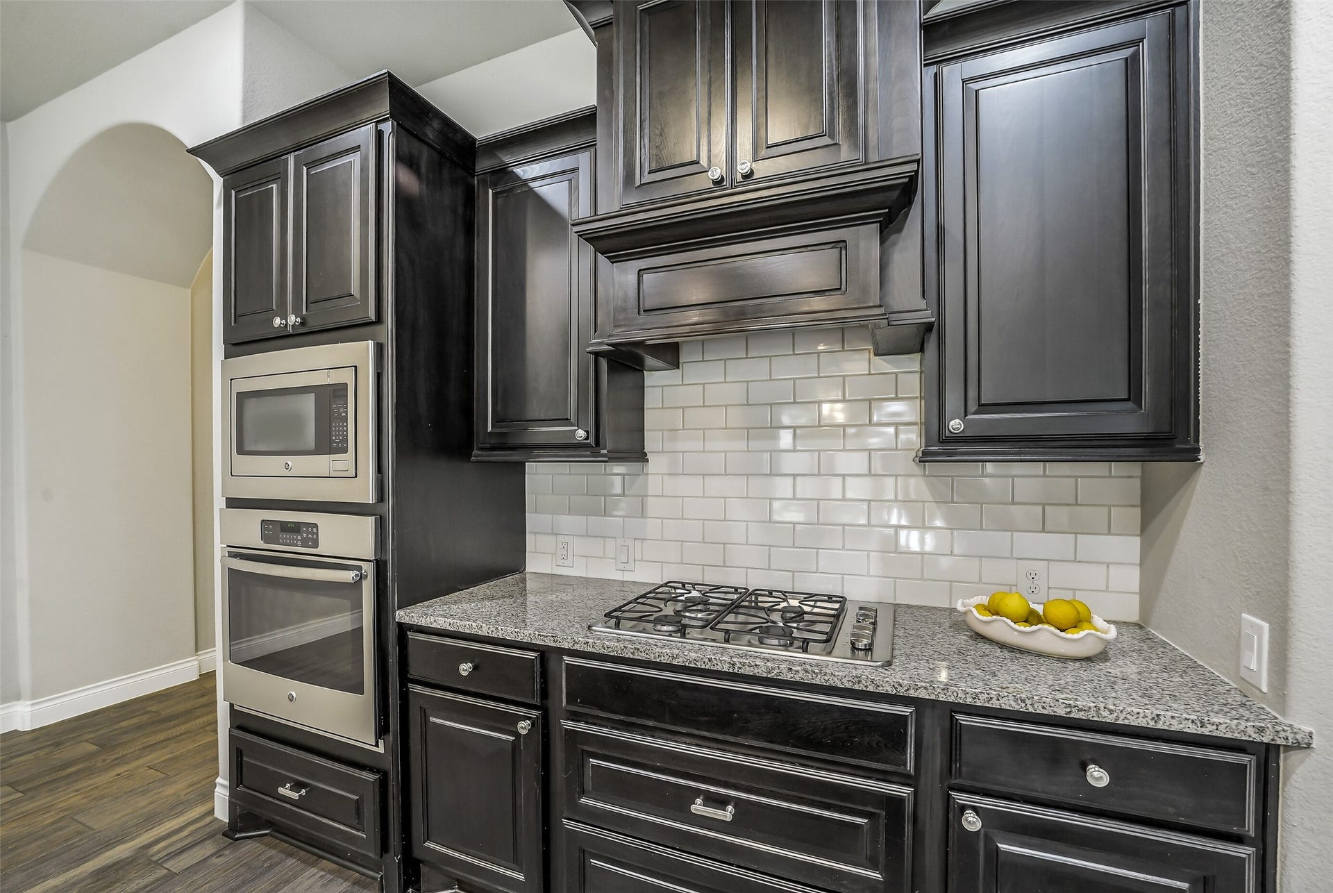 16818 Headwaters Forest Drive, Humble, TX 77346 Chef-inspired kitchen with gas cooktop, built-in oven and microwave, granite countertops, subway tile backsplash, and custom cabinetry.