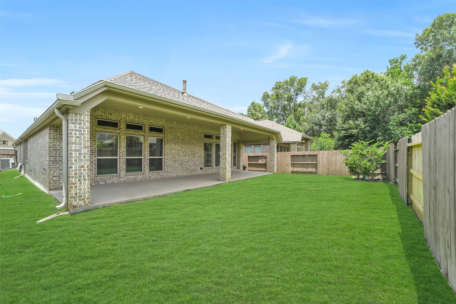 16818 Headwaters Forest Drive, Humble, TX 77346 Fully fenced backyard with lush green space and an expansive covered patio, offering the perfect setting for outdoor entertaining and everyday enjoyment.