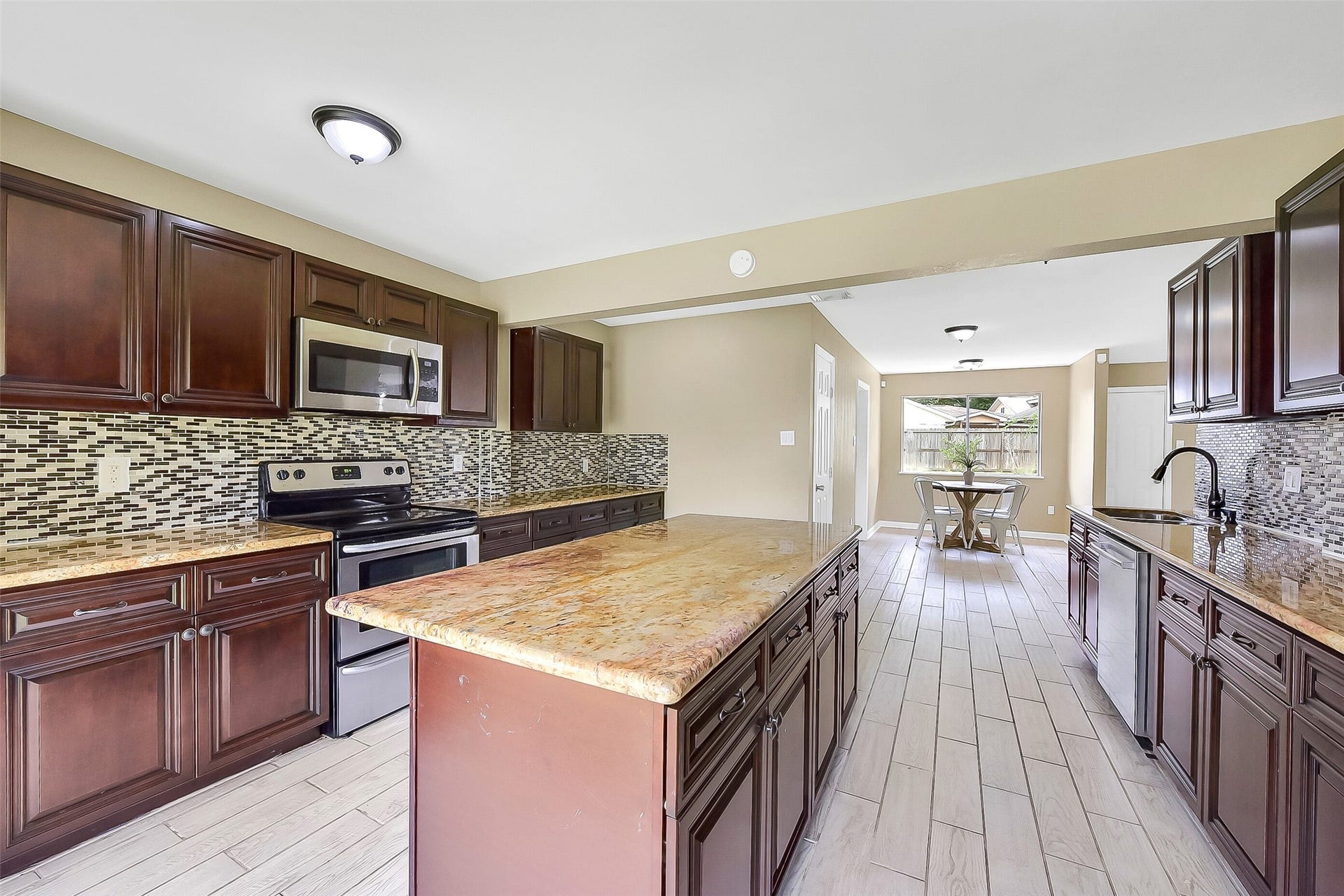 15503 Wandering Trail, Friendswood, TX 77546 This updated kitchen features rich wood cabinetry, exotic granite countertops, a stylish mosaic glass tile backsplash, stainless appliances, and a large center island with extra storage and workspace.