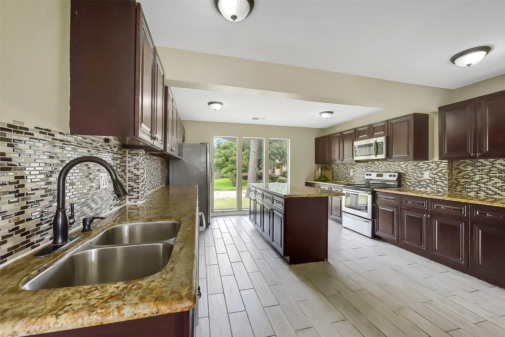 15503 Wandering Trail, Friendswood, TX 77546 This kitchen is designed with the cook in mind, offering a full suite of stainless steel appliances including a built-in microwave, smooth glass top electric range, oven, and dishwasher. Rich wood cabinetry provides abundant storage, while granite countertops and a large center island create ample prep space.