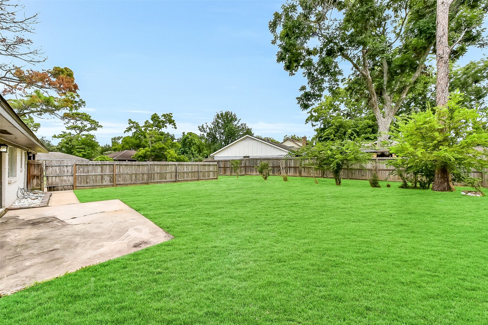 15503 Wandering Trail, Friendswood, TX 77546 Expansive fenced backyard with a concrete patio area, mature trees, and plenty of open green spaceperfect for outdoor living, gardening, or entertaining. Also includes a whole-house Generac generator for peace of mind.