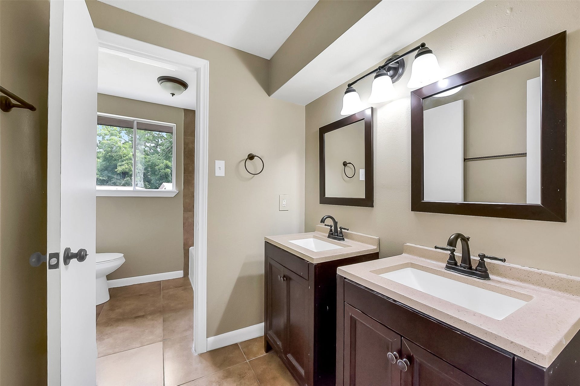 15503 Wandering Trail, Friendswood, TX 77546 Upstairs full bathroom offers dual vanities with framed mirrors, updated fixtures, and a separate area with the tub/shower with a tile surround and toilet for added convenience.