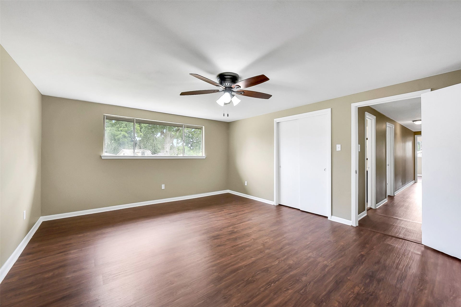 15503 Wandering Trail, Friendswood, TX 77546 The fifth and final bedroom is generously sized and features wood-look flooring, a ceiling fan, and a large window that fills the space with natural light.
