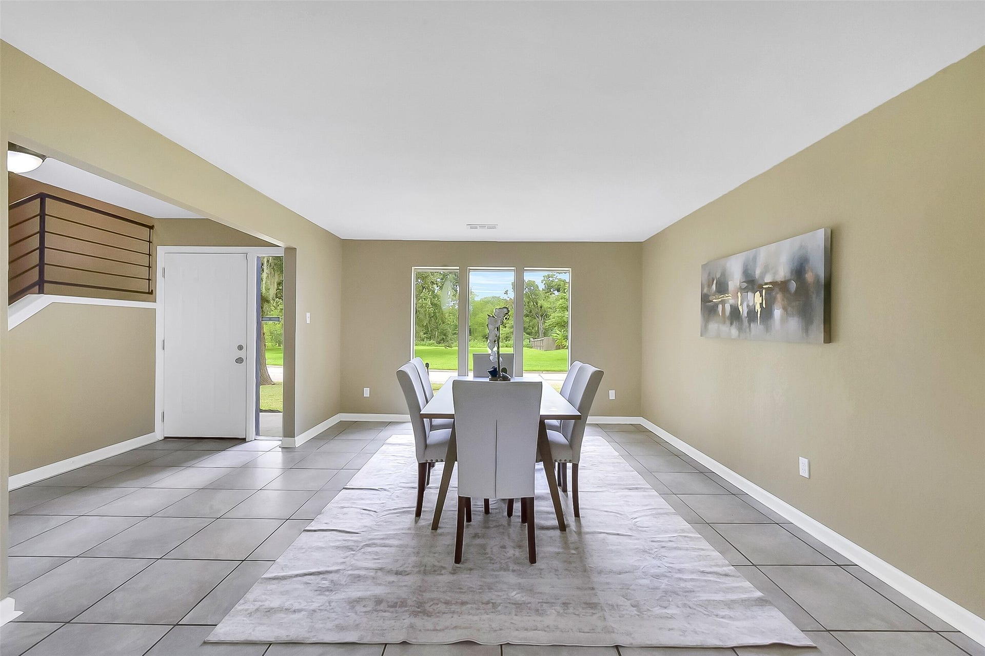 15503 Wandering Trail, Friendswood, TX 77546 Formal dining room with neutral paint, large-format tile floors, and abundant natural light from a trio of wide picture windows overlooking the front yard.