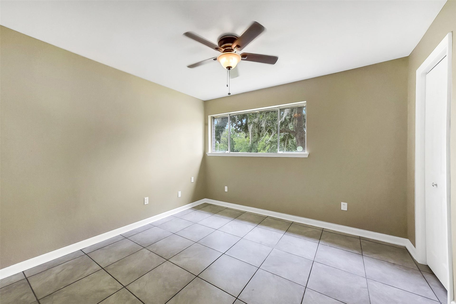 15503 Wandering Trail, Friendswood, TX 77546 First-floor guest bedroom featuring neutral paint, tile flooring, a ceiling fan, and a large window that fills the space with natural light.