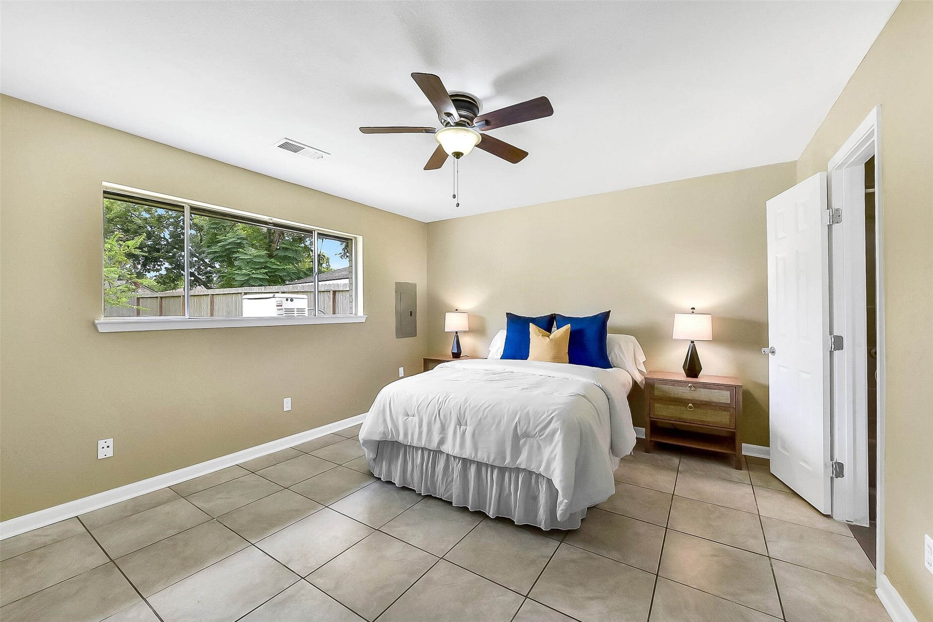 15503 Wandering Trail, Friendswood, TX 77546 This first-floor primary suite offers a peaceful retreat with neutral tones, tile flooring, a ceiling fan, and a large window that fills the room with natural light. An en-suite bath provides added privacy and convenience.