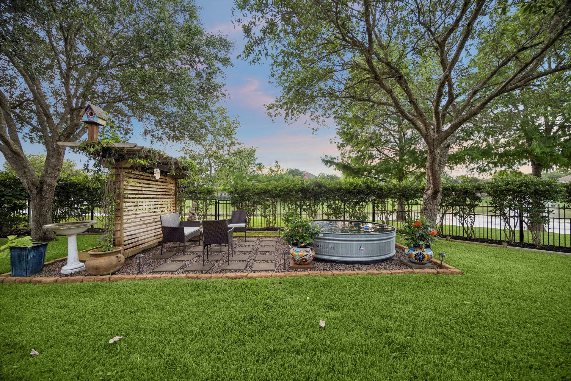 3102 London Lane, Missouri City, TX 77459 Lush landscaping and mature trees frame the hardscaped entertaining spot; the lake provides a scenic backdrop.