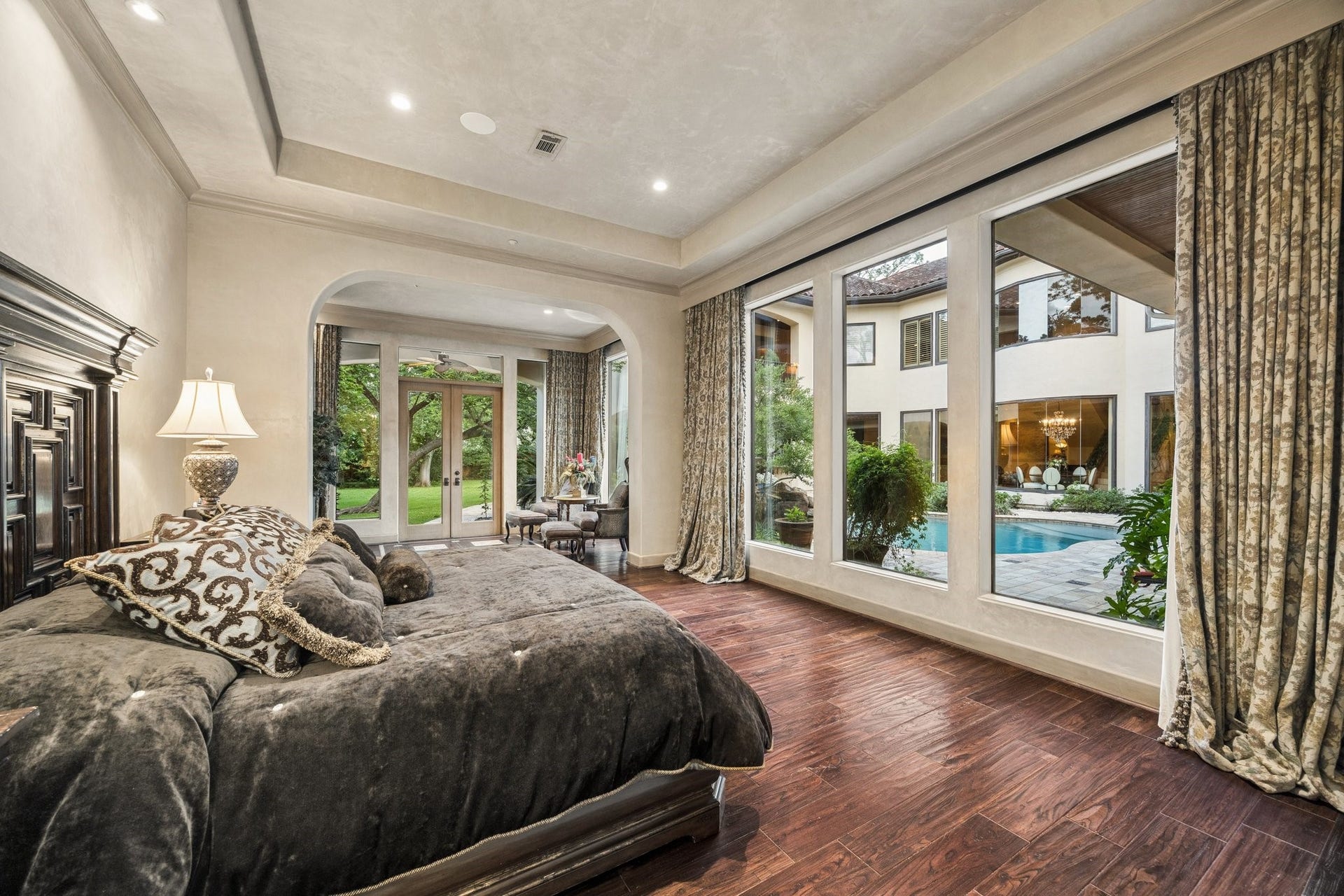 2 Lacewood Lane, Piney Point Village, TX 77024 Luxurious owners suite featuring rich wood flooring, a private sitting area, and serene views over the pool and courtyard.