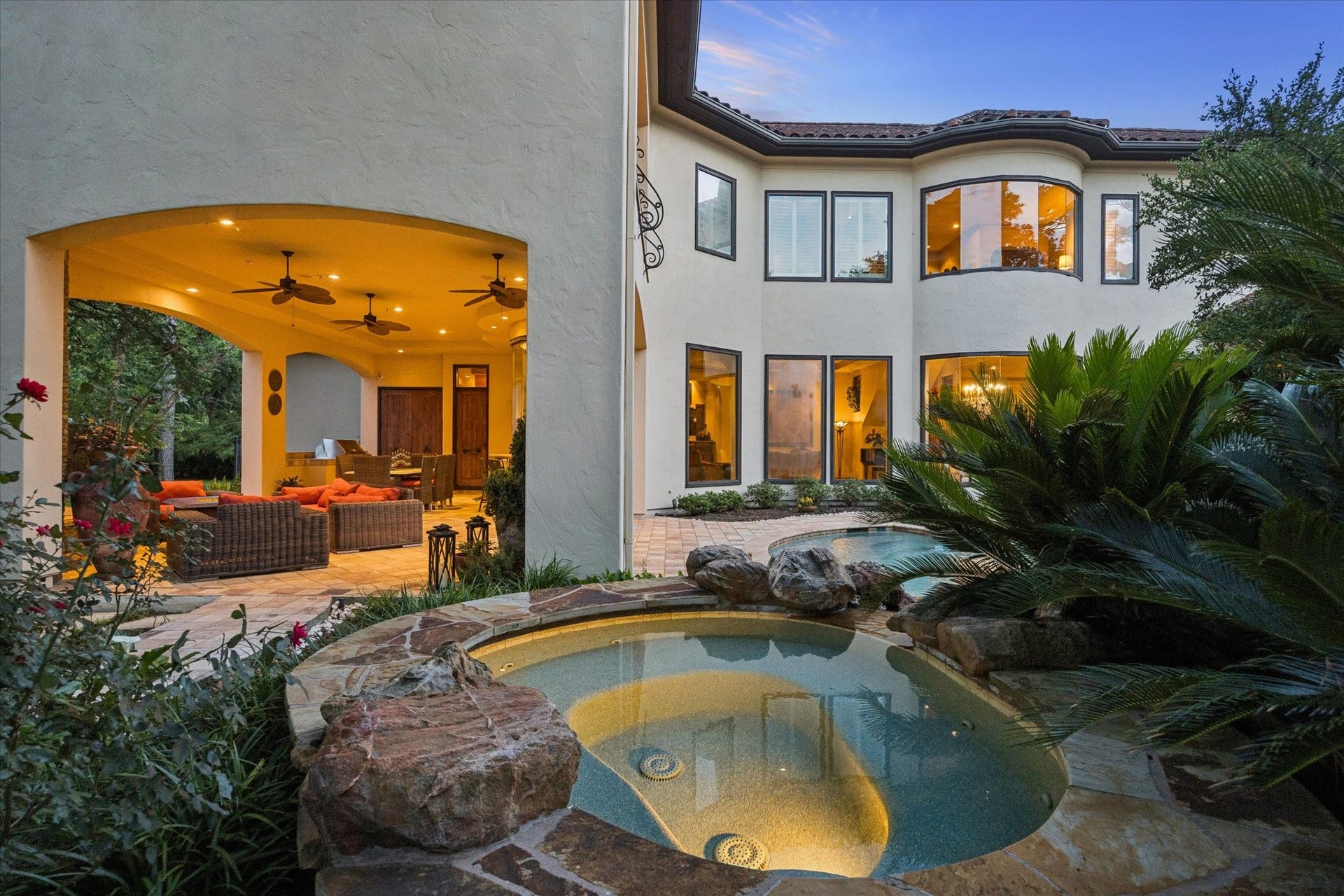 2 Lacewood Lane, Piney Point Village, TX 77024 Resort-style pool and spa surrounded by lush landscaping, warm evening lighting, and seamless access to the covered loggia.
