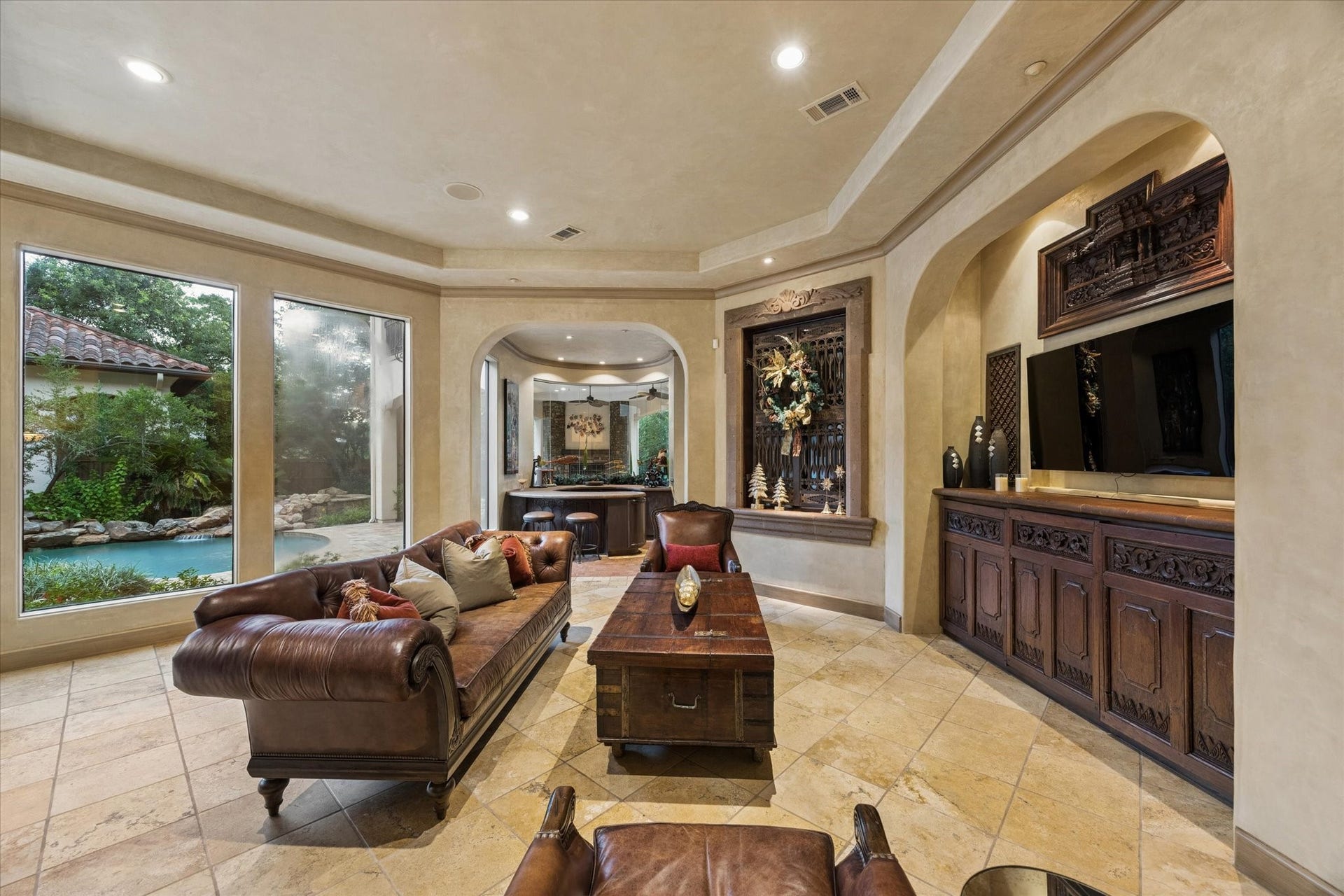 2 Lacewood Lane, Piney Point Village, TX 77024 Richly detailed den with built-in media cabinetry, serene pool views, and convenient access to the bar area.